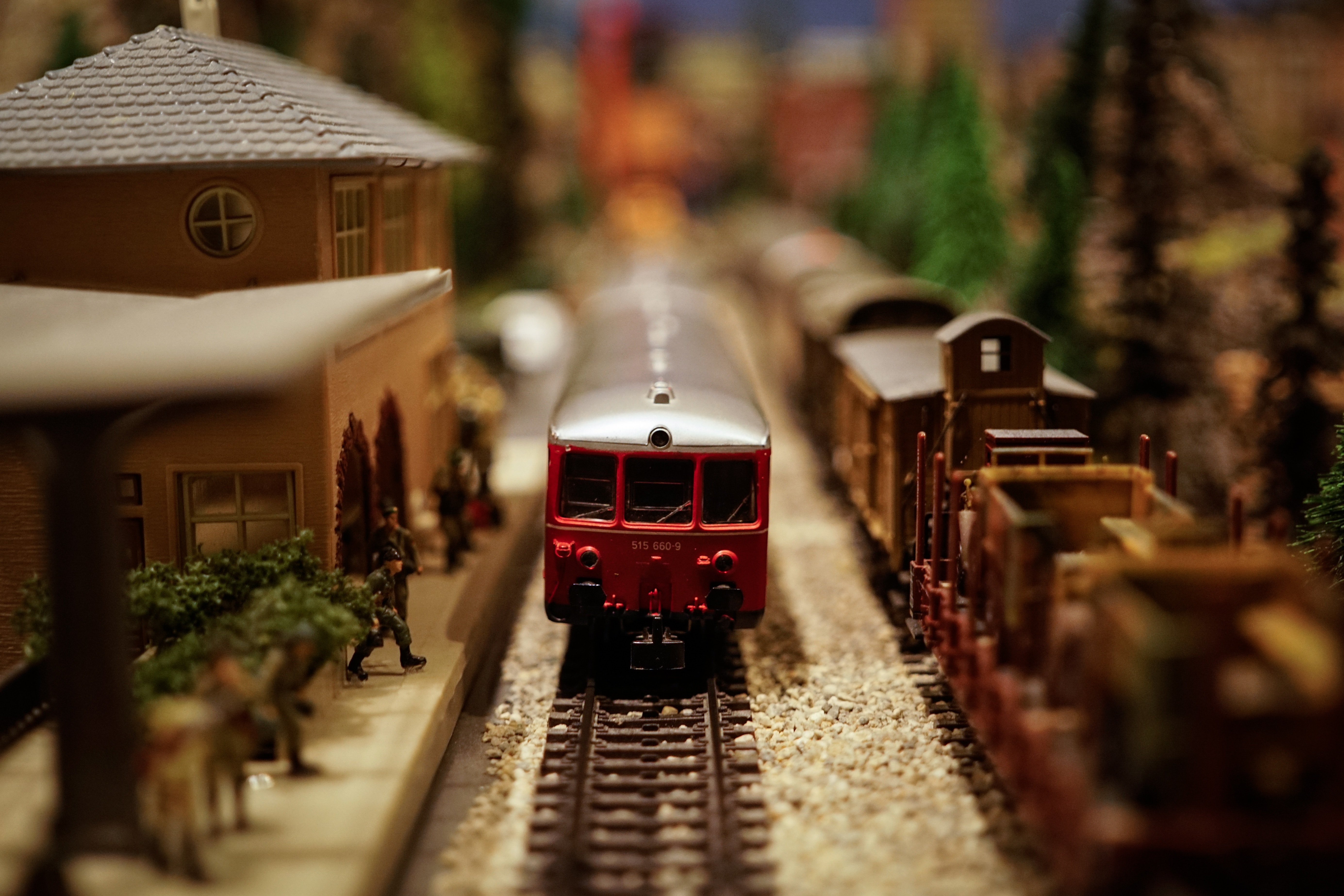 Model train station with red engine and freight cars HD Wallpaper