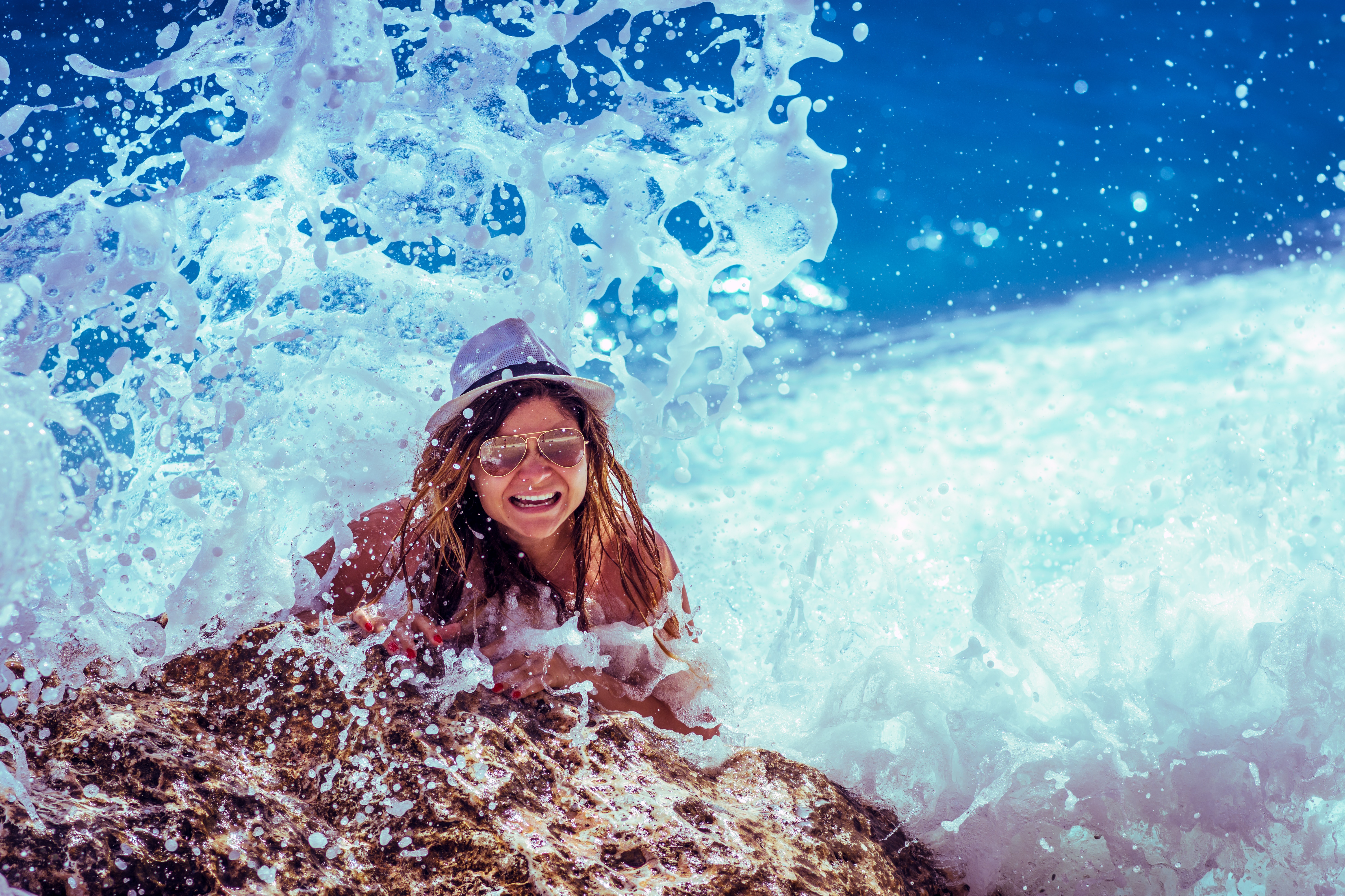 Woman in a hat and sunglasses splashes in ocean waves HD Wallpaper