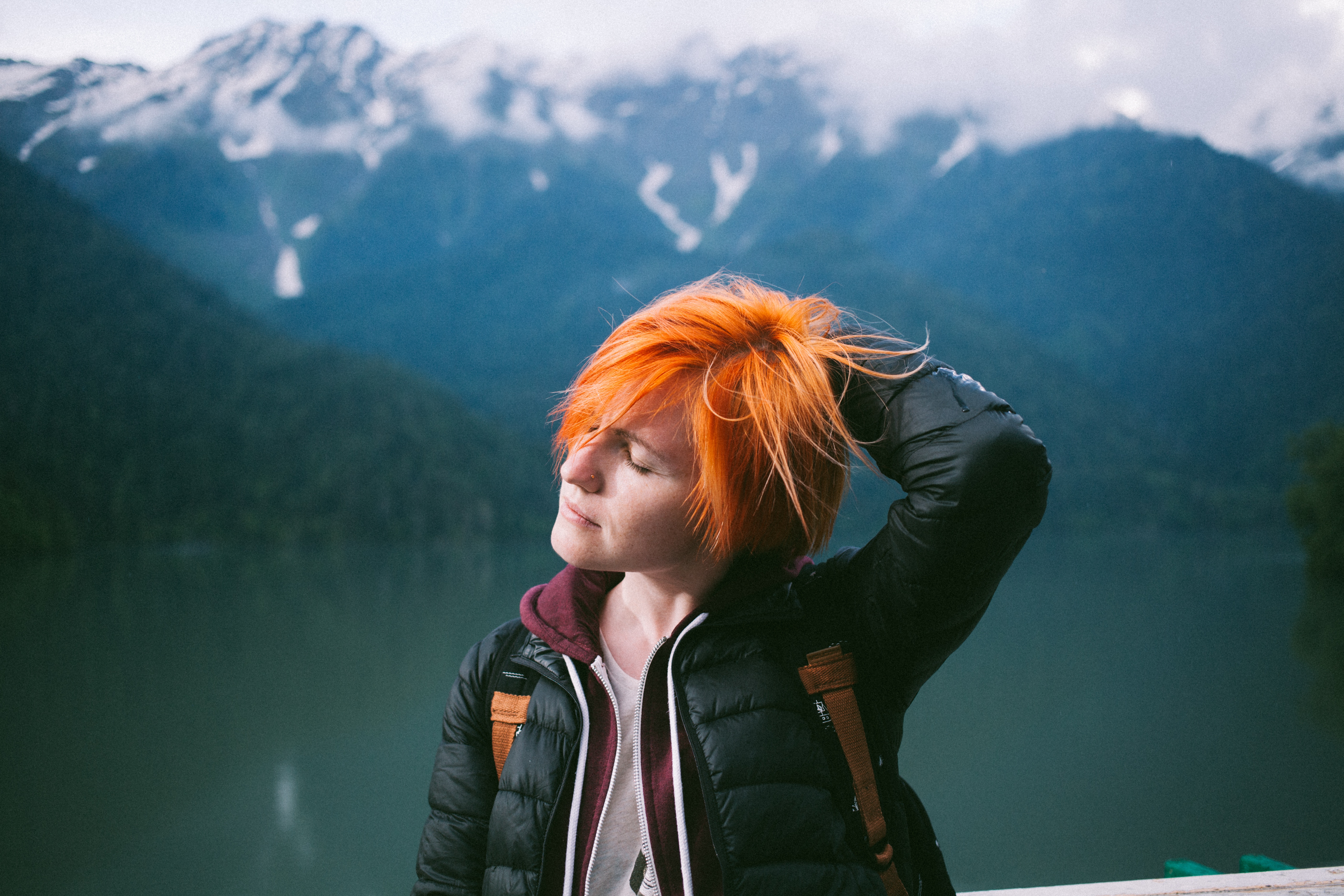 Woman with orange hair by a lake with mountains HD Wallpaper