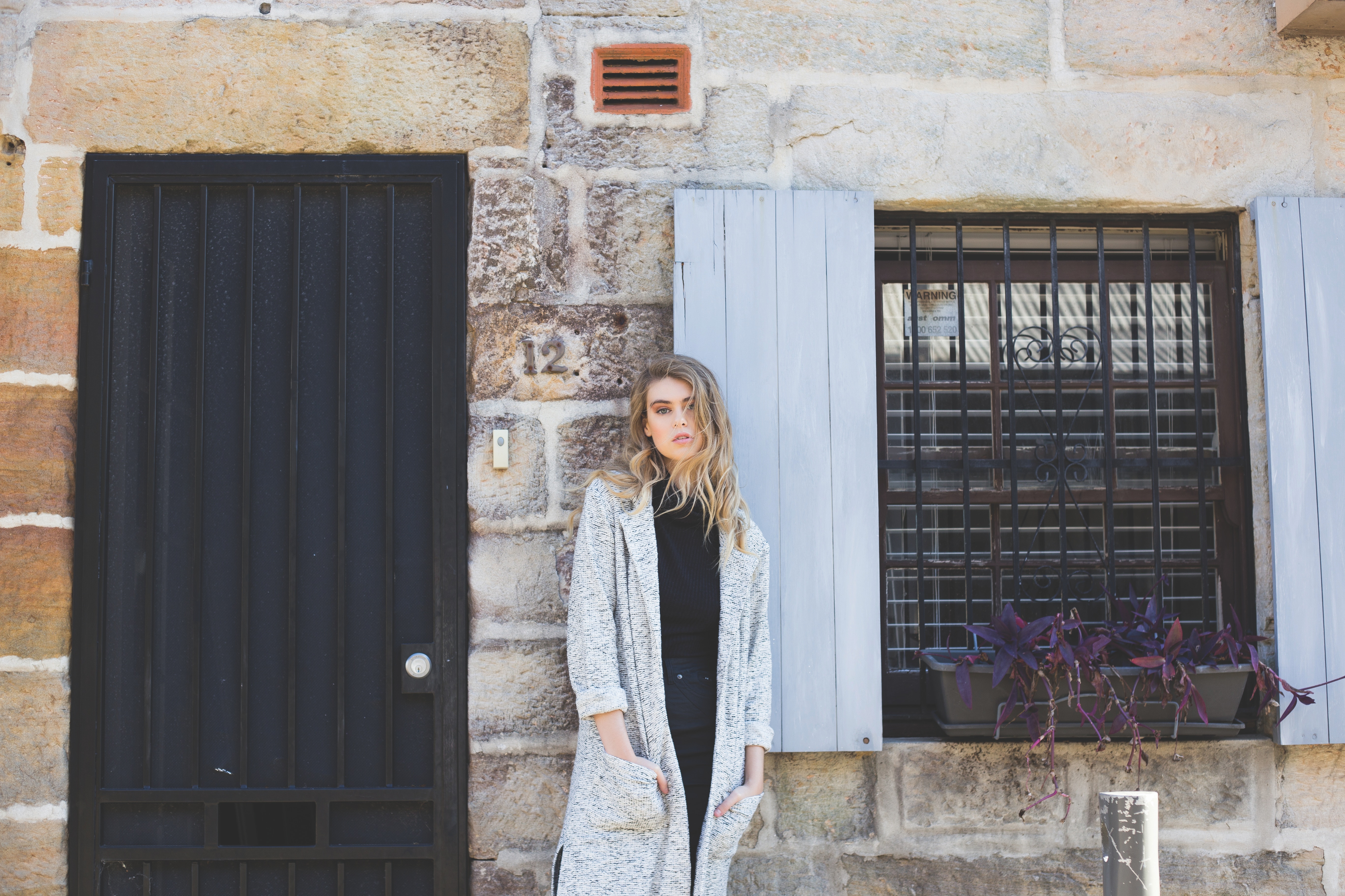 Woman in a coat standing by a stone building HD Wallpaper