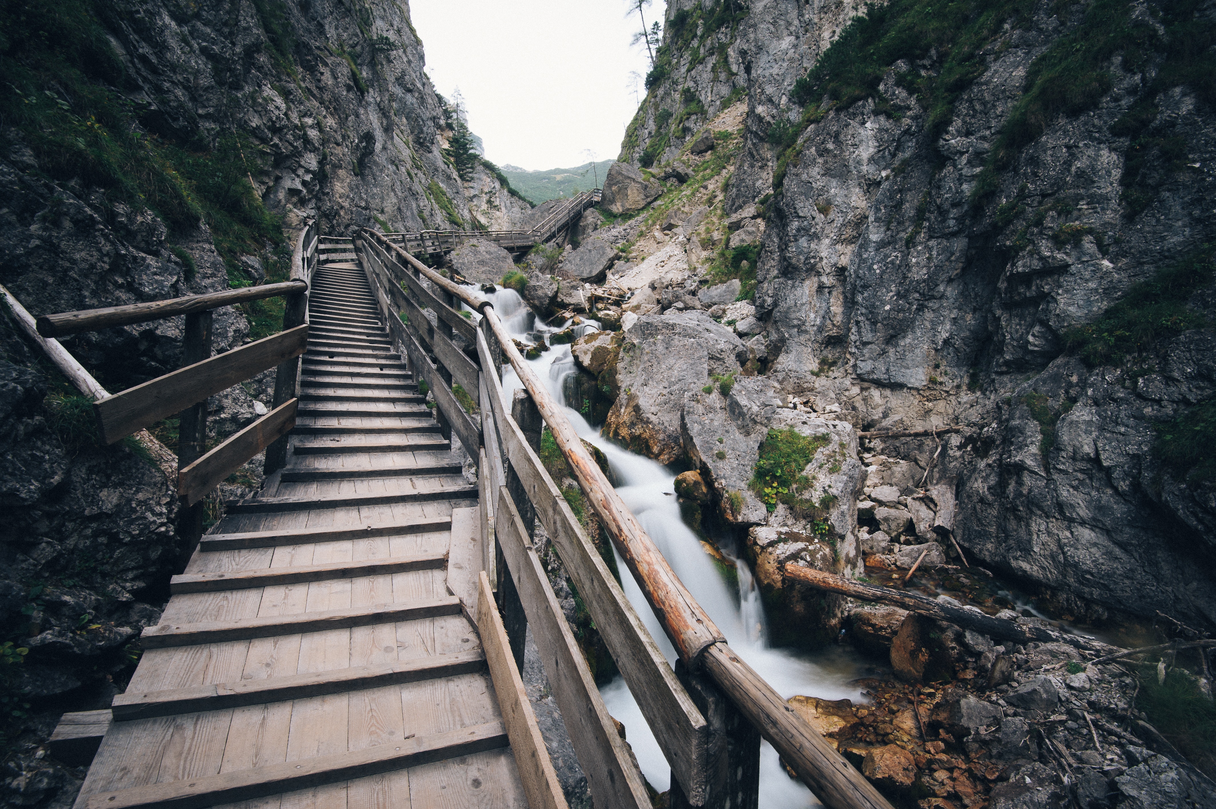Wooden walkway along a rocky mountain stream HD Wallpaper