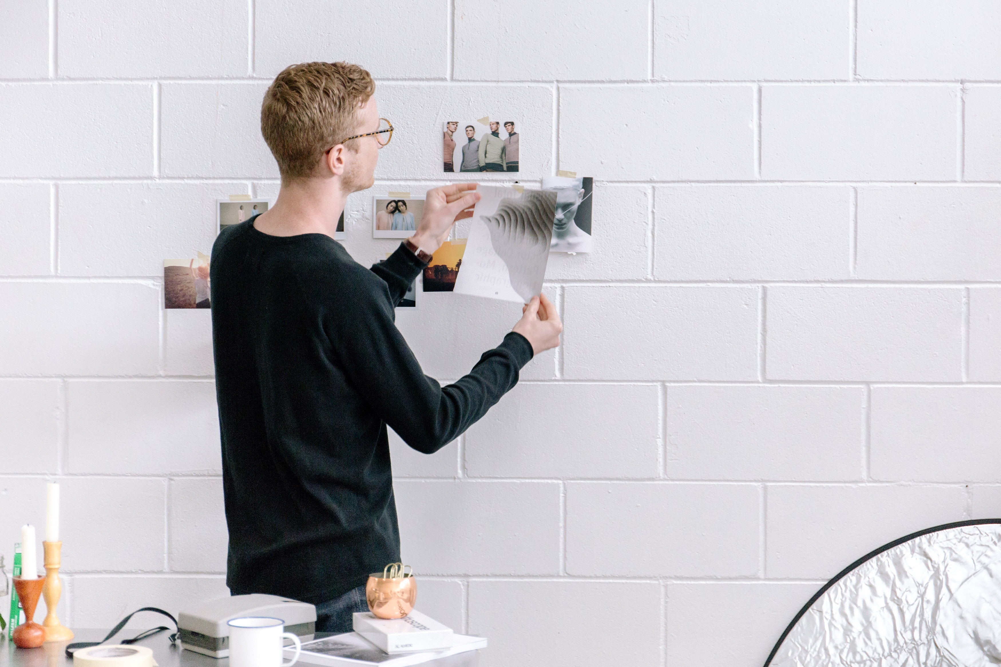 Man hanging photos on a white brick wall HD Wallpaper