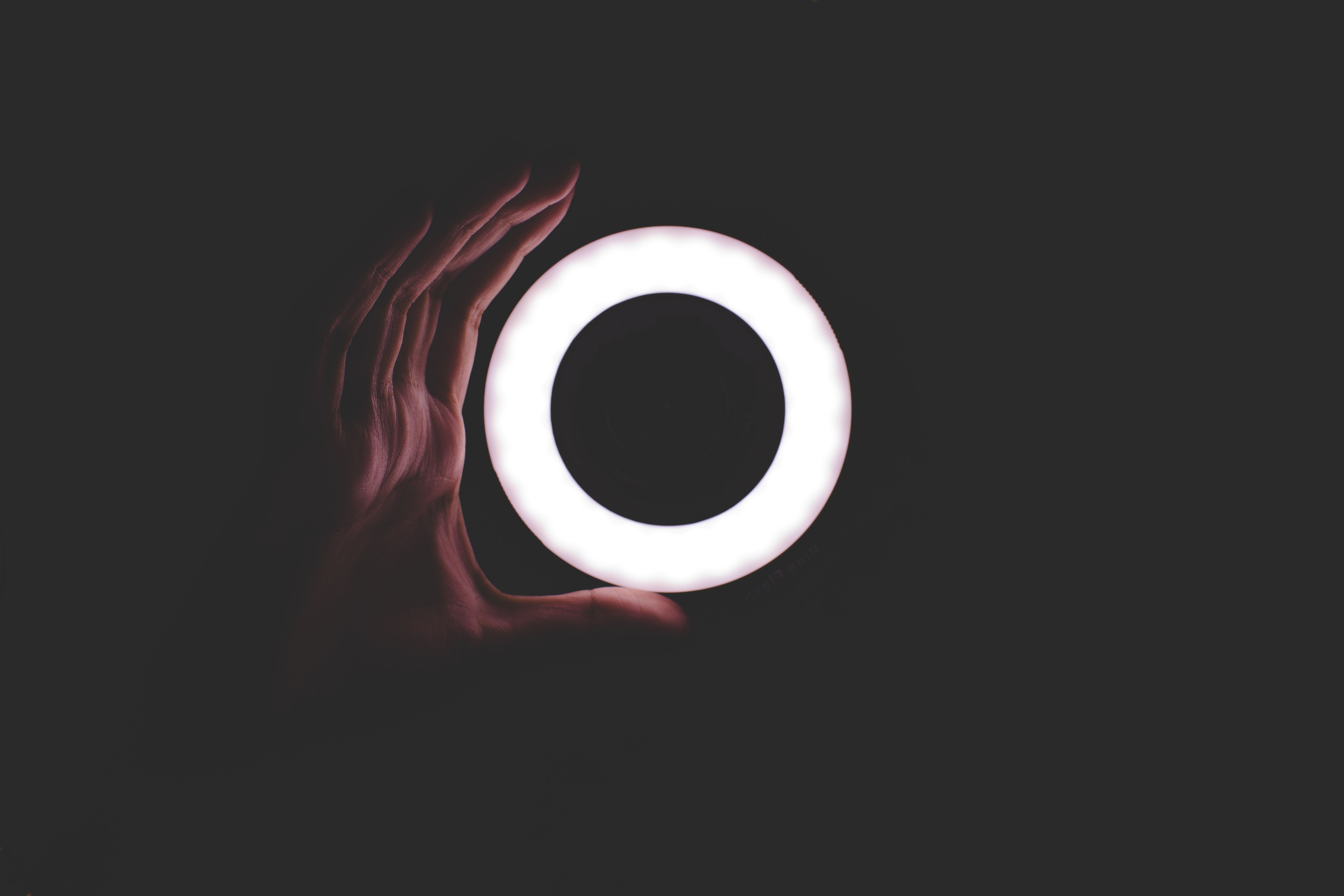 Hand holding a glowing ring light in the dark HD Wallpaper