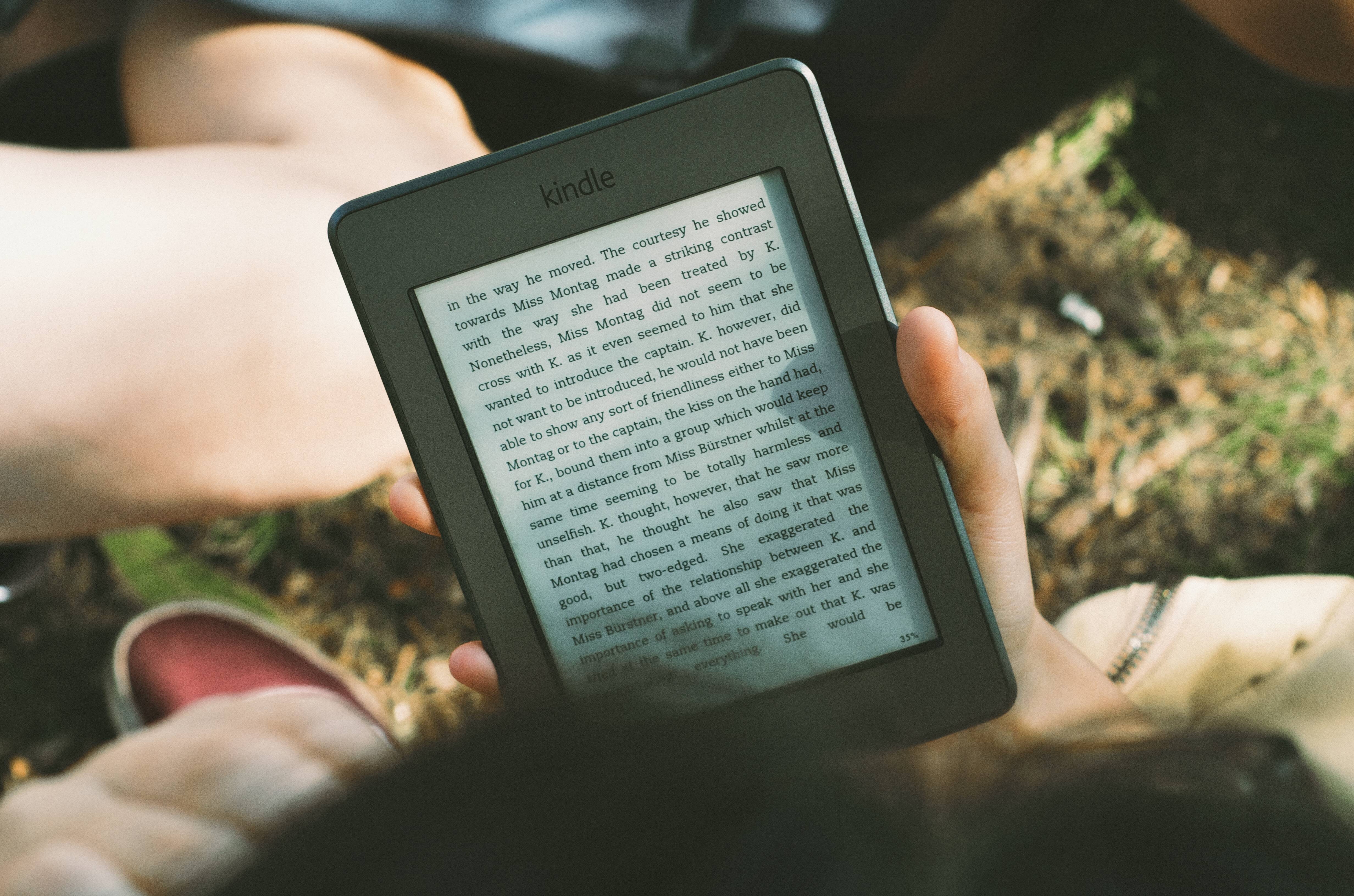 Person reading a Kindle outdoors HD Wallpaper