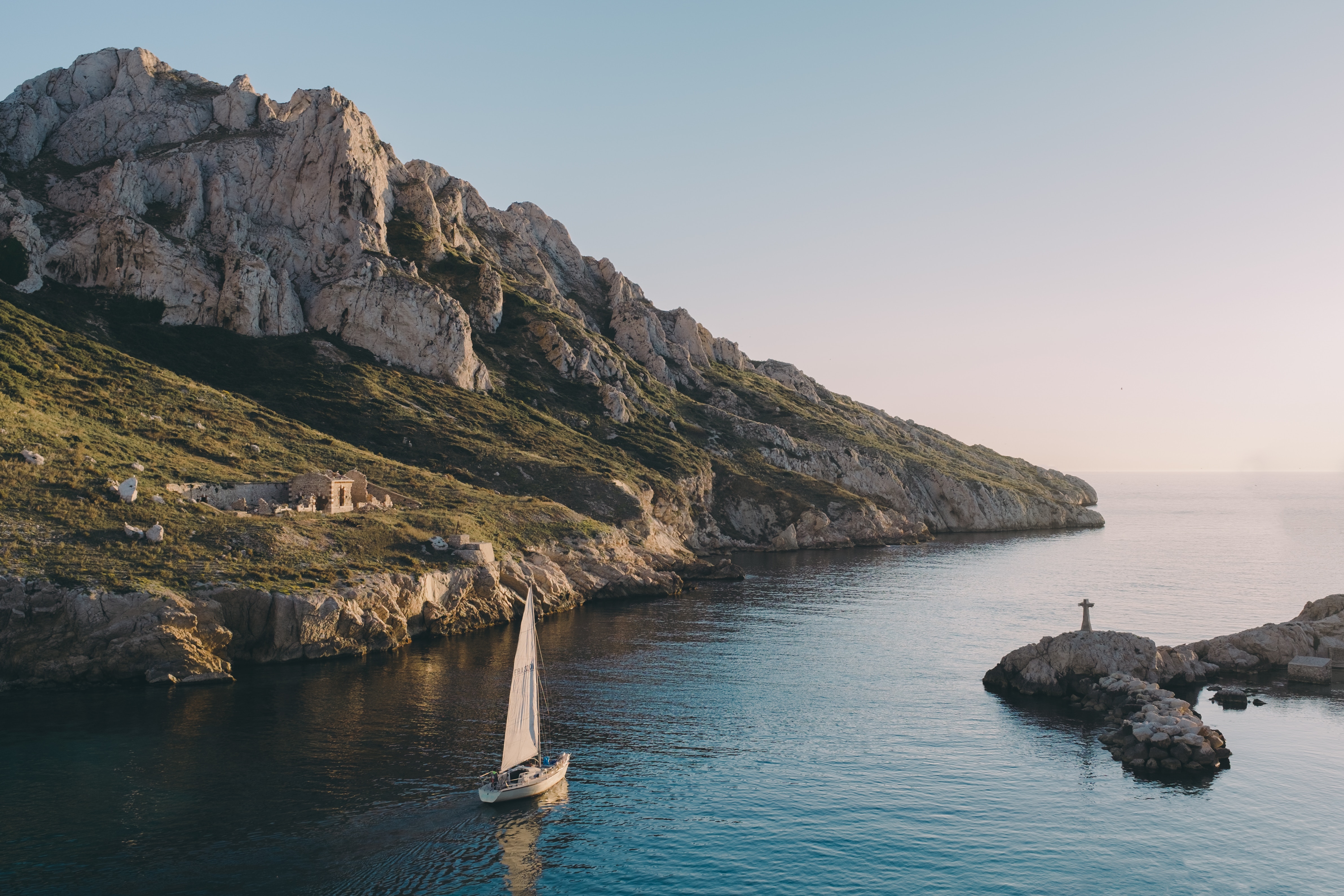 Sailboat near rocky coast and mountain HD Wallpaper