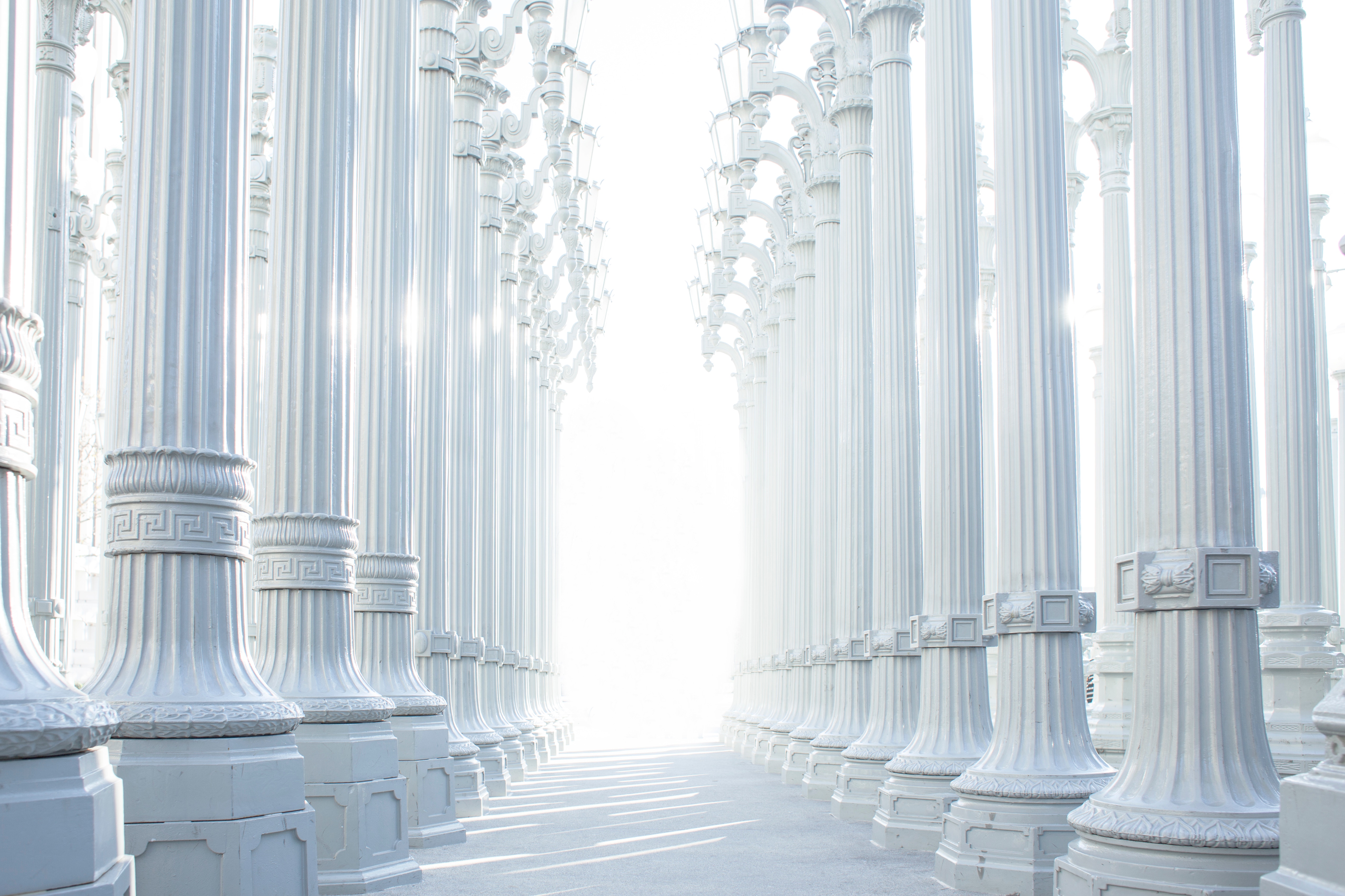 White columns forming a pathway towards bright light HD Wallpaper