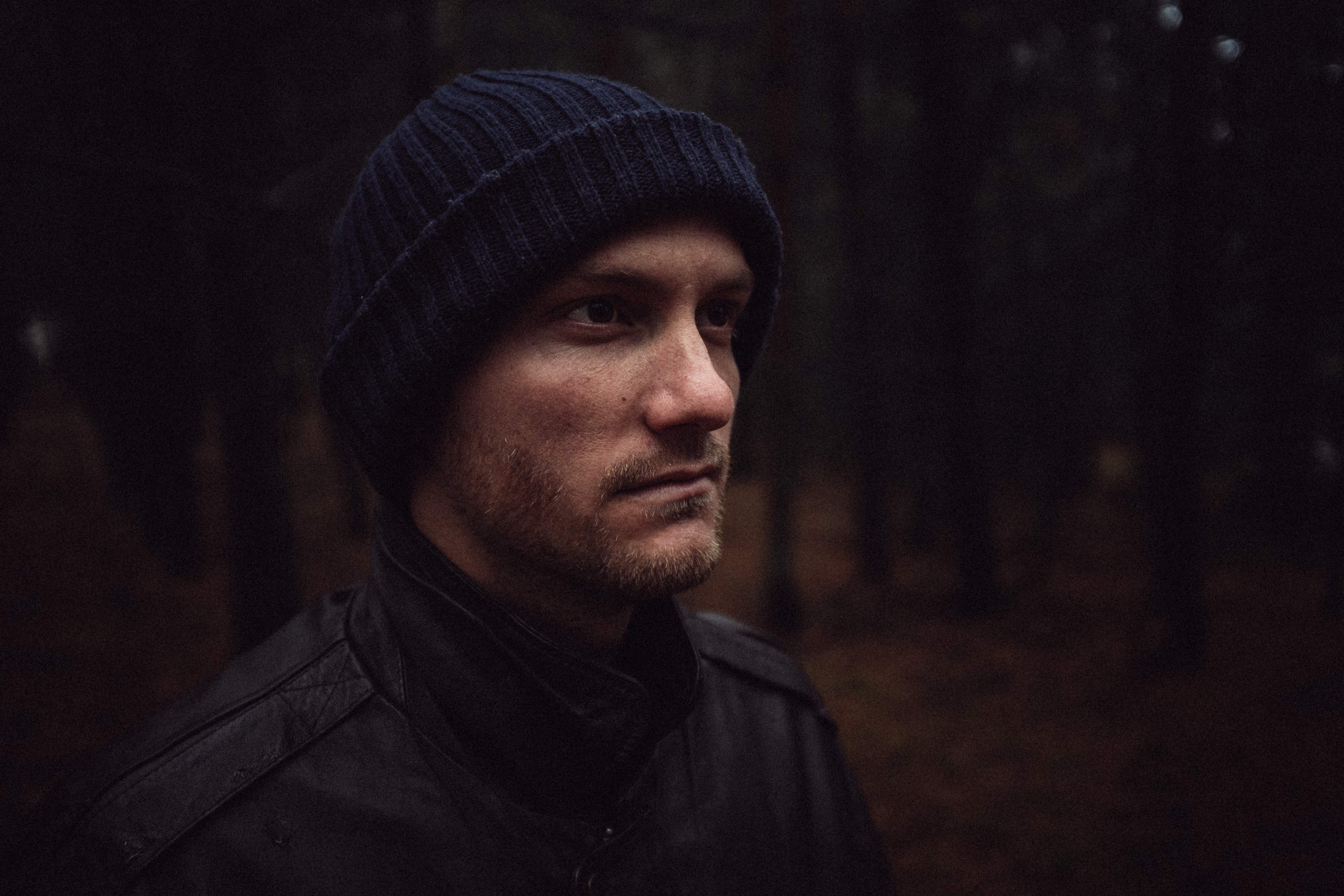 Man wearing a beanie and jacket in a forest HD Wallpaper