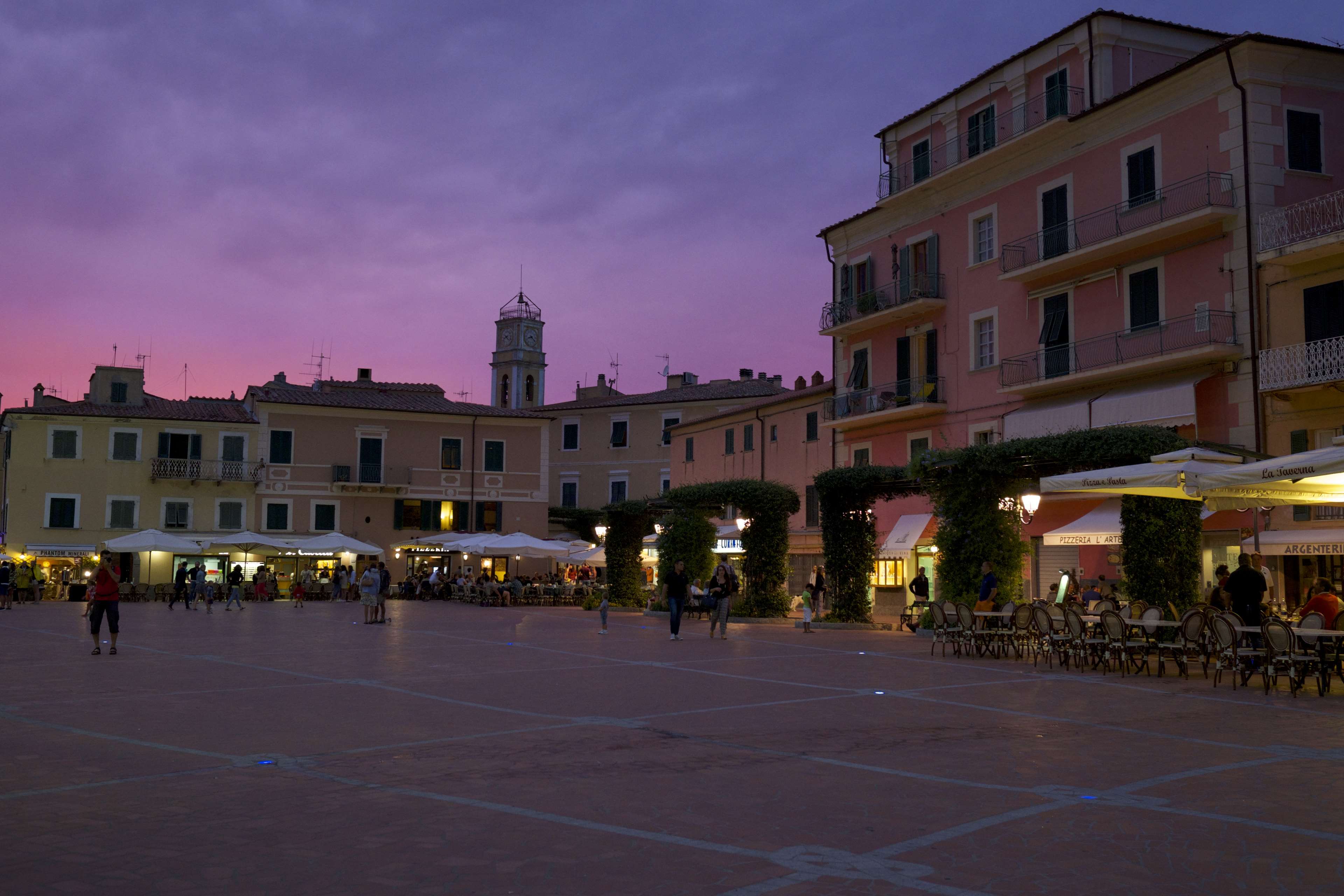 Town square at dusk with buildings and outdoor seating HD Wallpaper