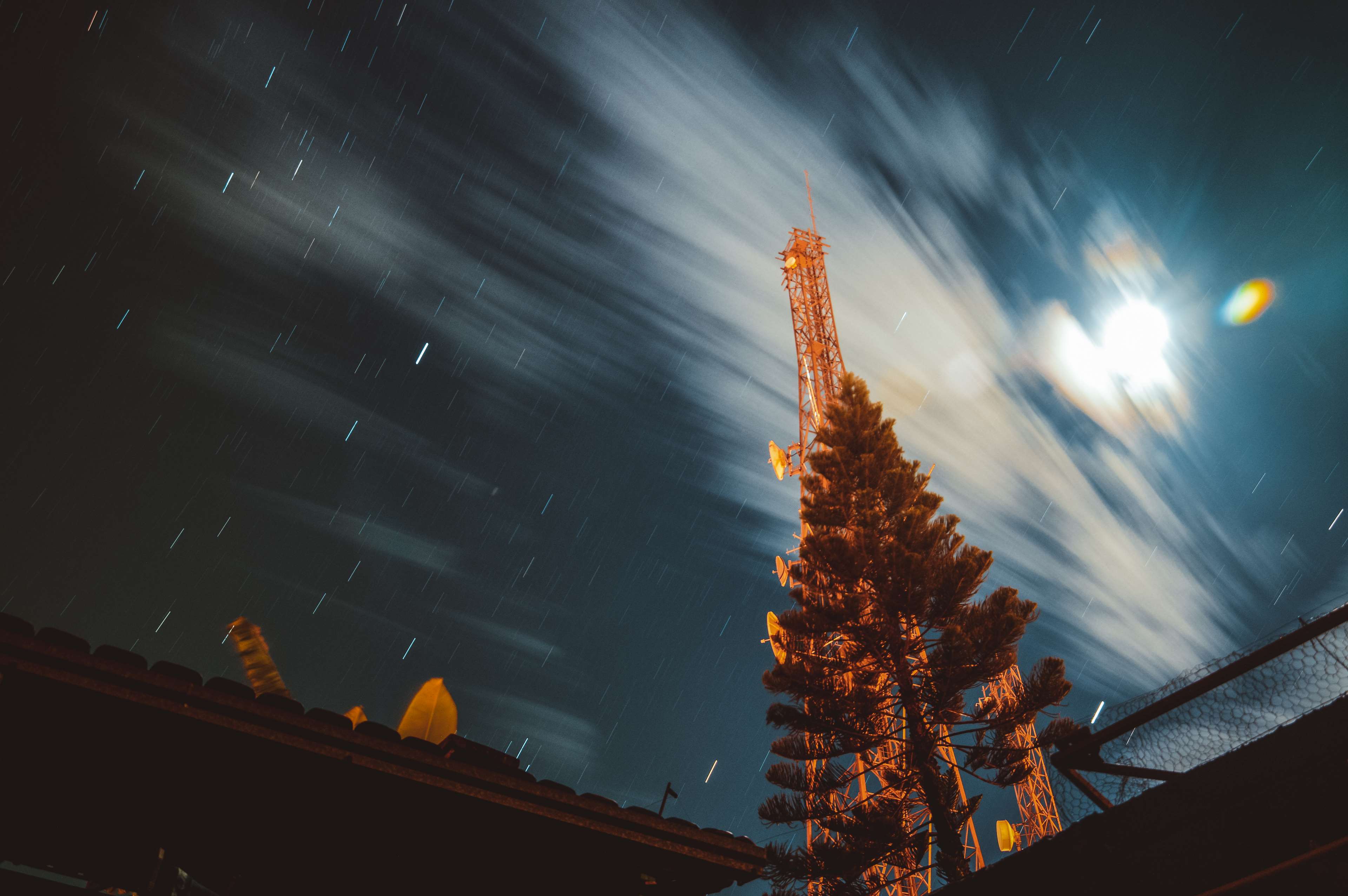 Long exposure night sky with stars and clouds over a cell tower HD Wallpaper
