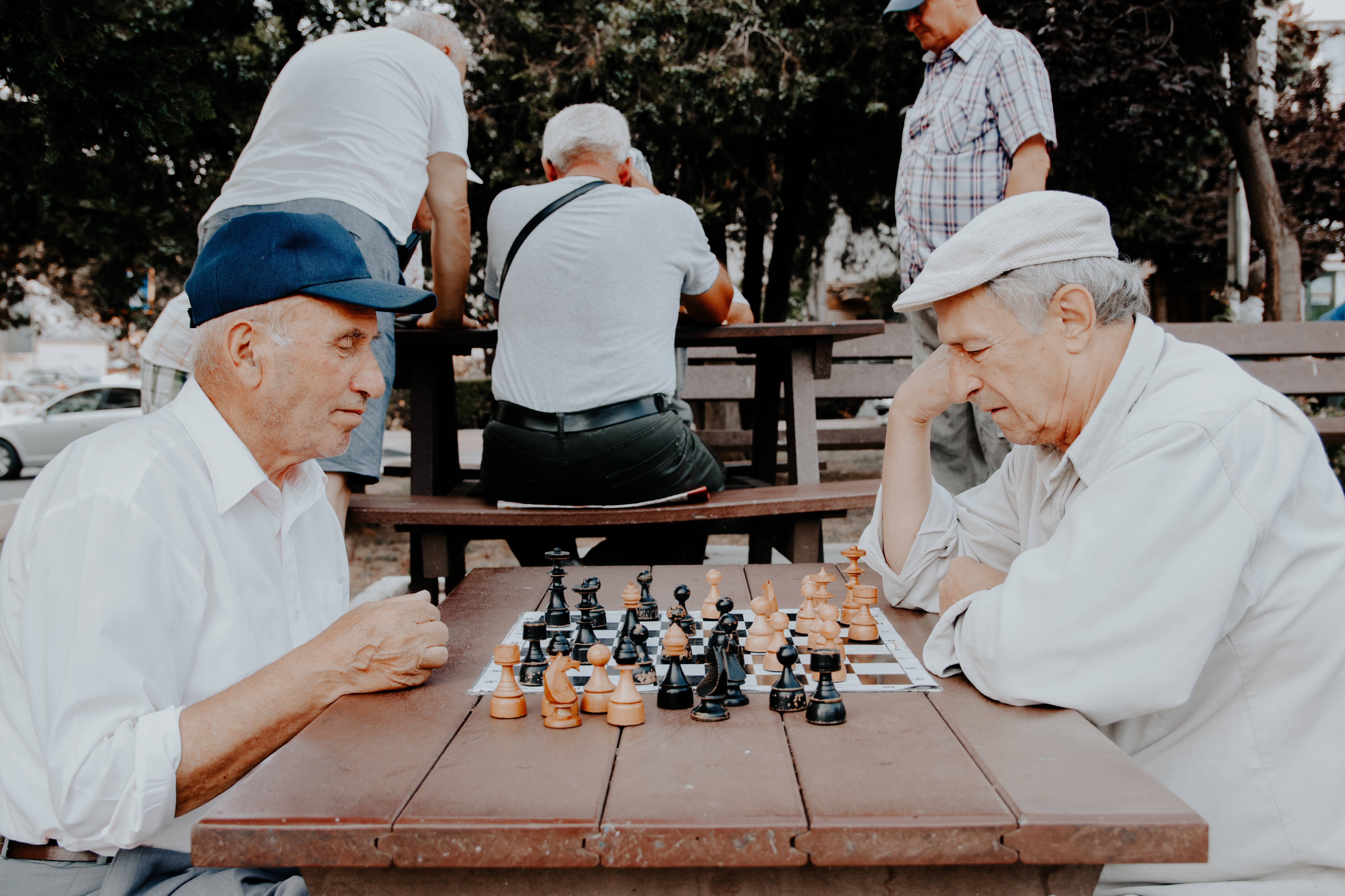 Elderly men playing chess in a park HD Wallpaper