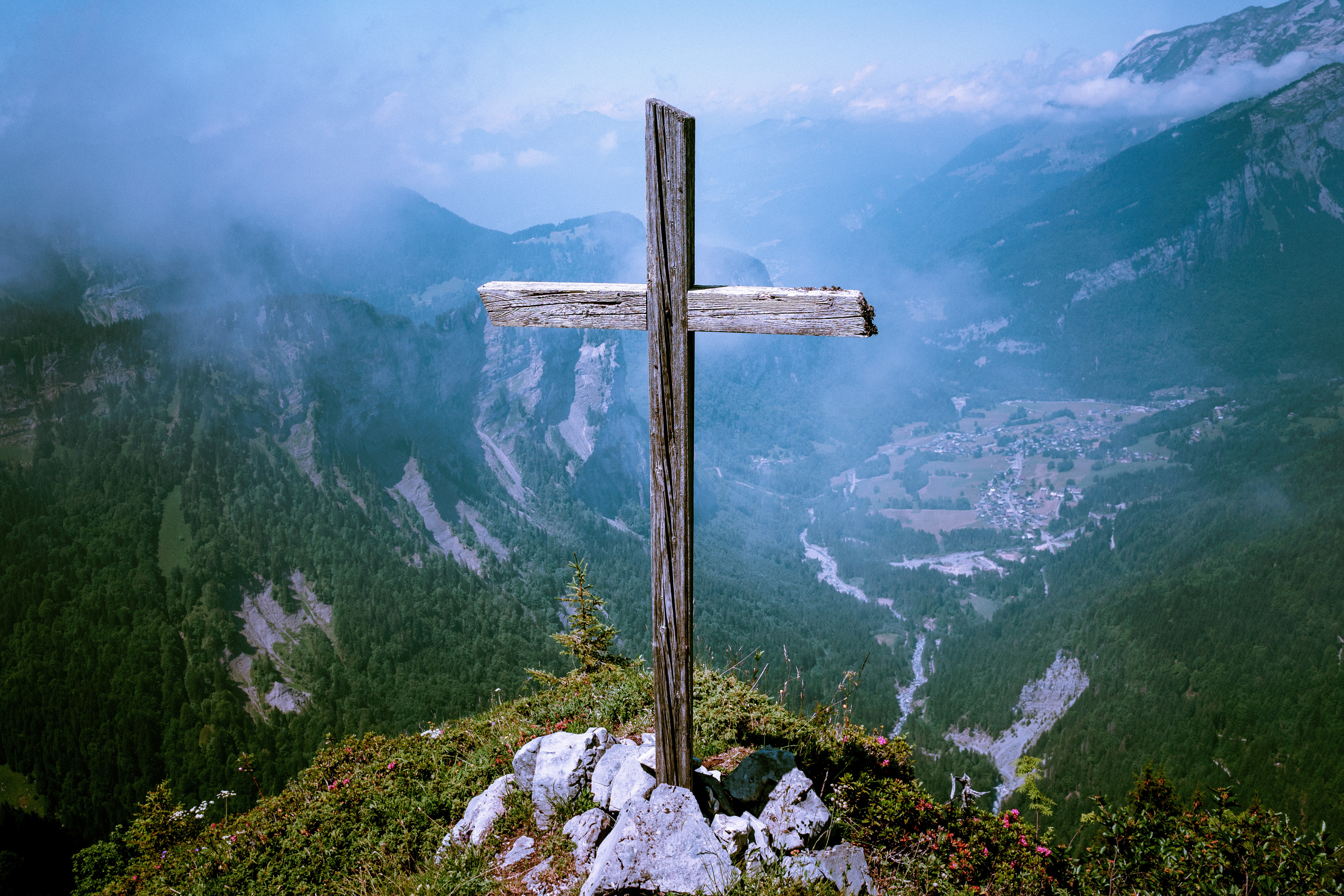 Wooden cross on a mountain summit overlooking a valley HD Wallpaper