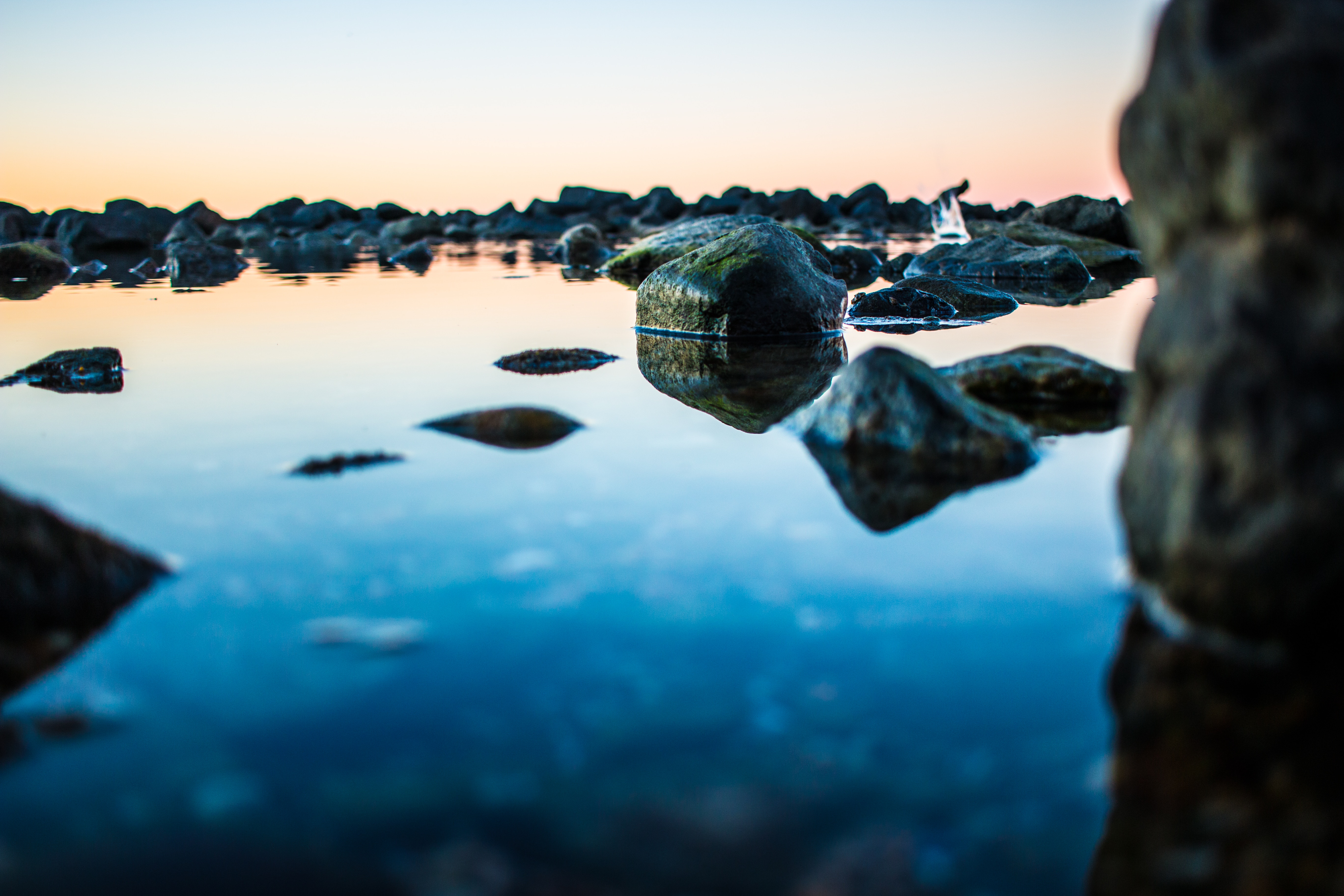 Rocks and reflections on a rocky shore at sunset HD Wallpaper