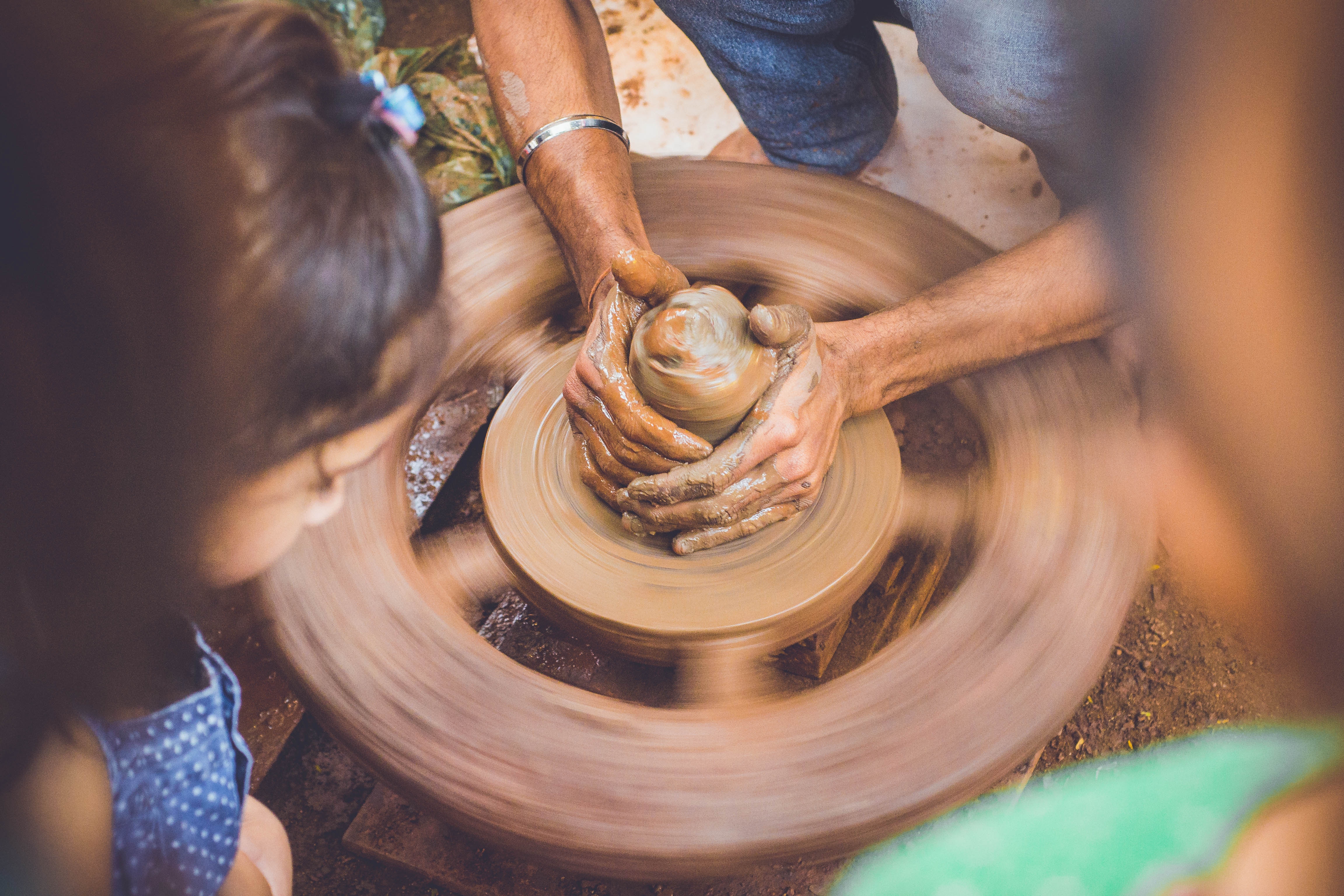 Potter working on a pottery wheel with children watching HD Wallpaper