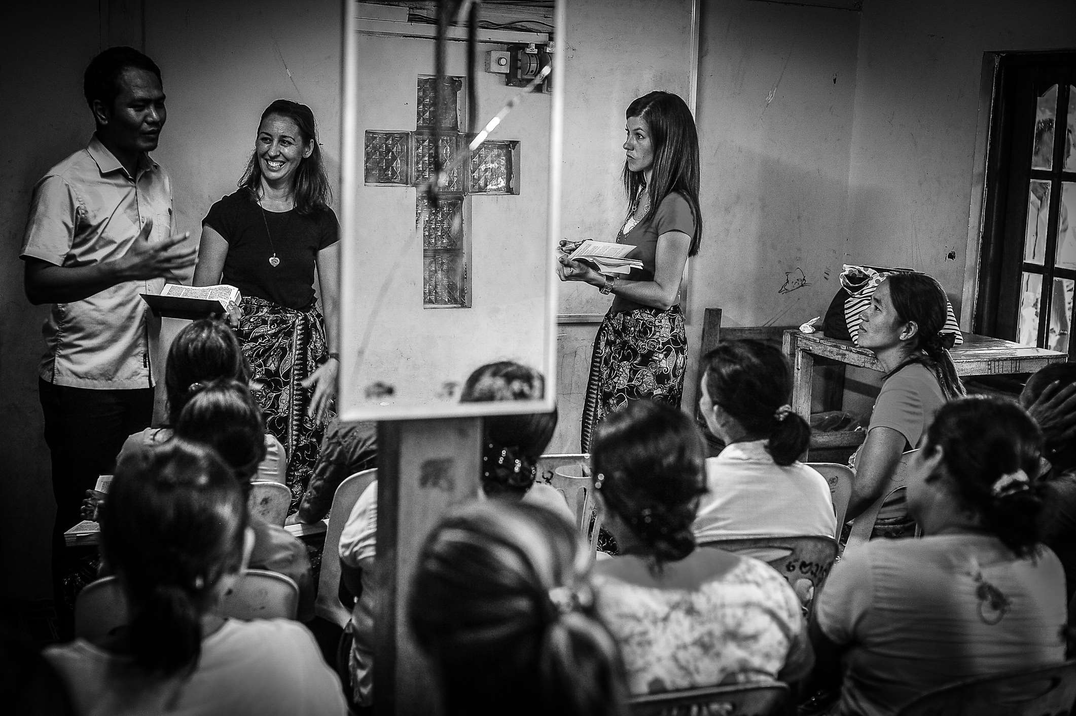 People gathered in a room for a presentation with a cross HD Wallpaper
