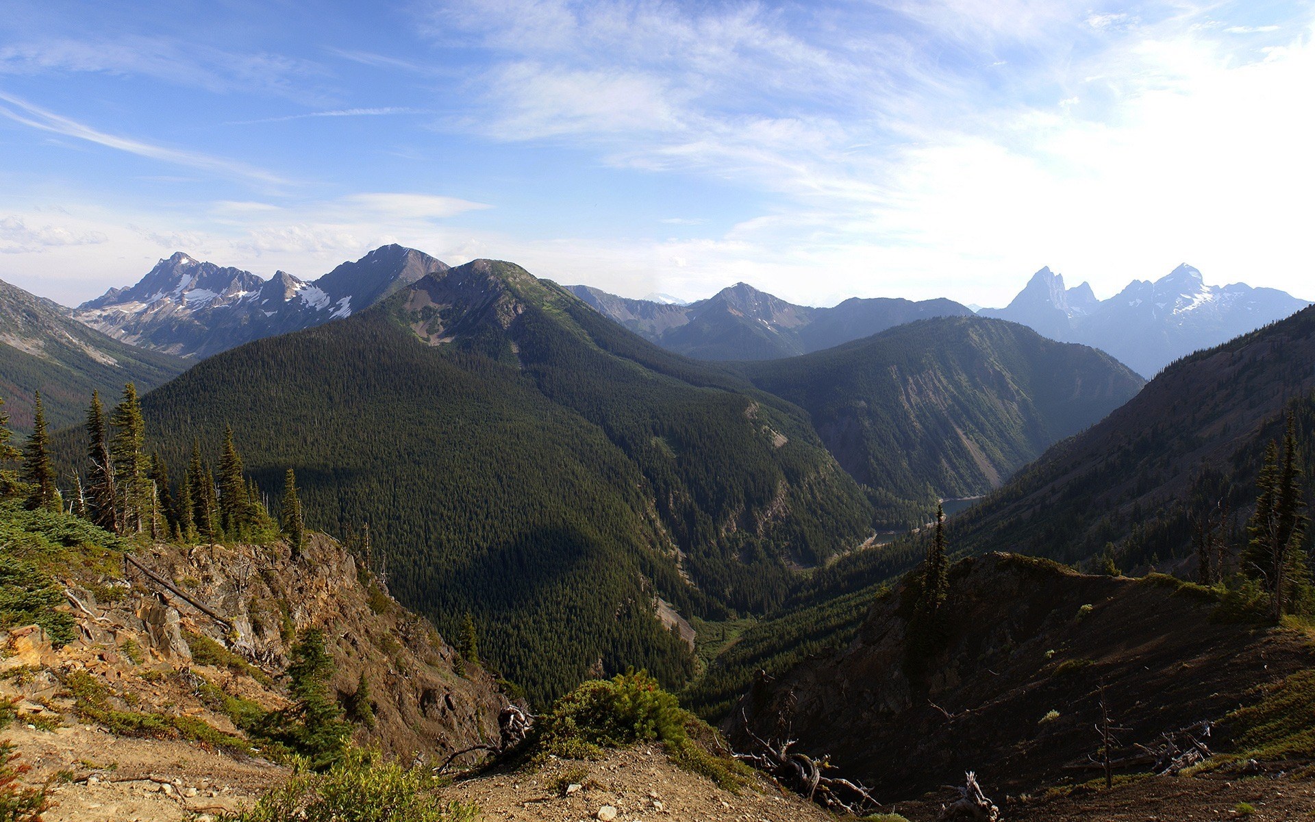 Panoramic view of forested mountains under a cloudy sky HD Wallpaper