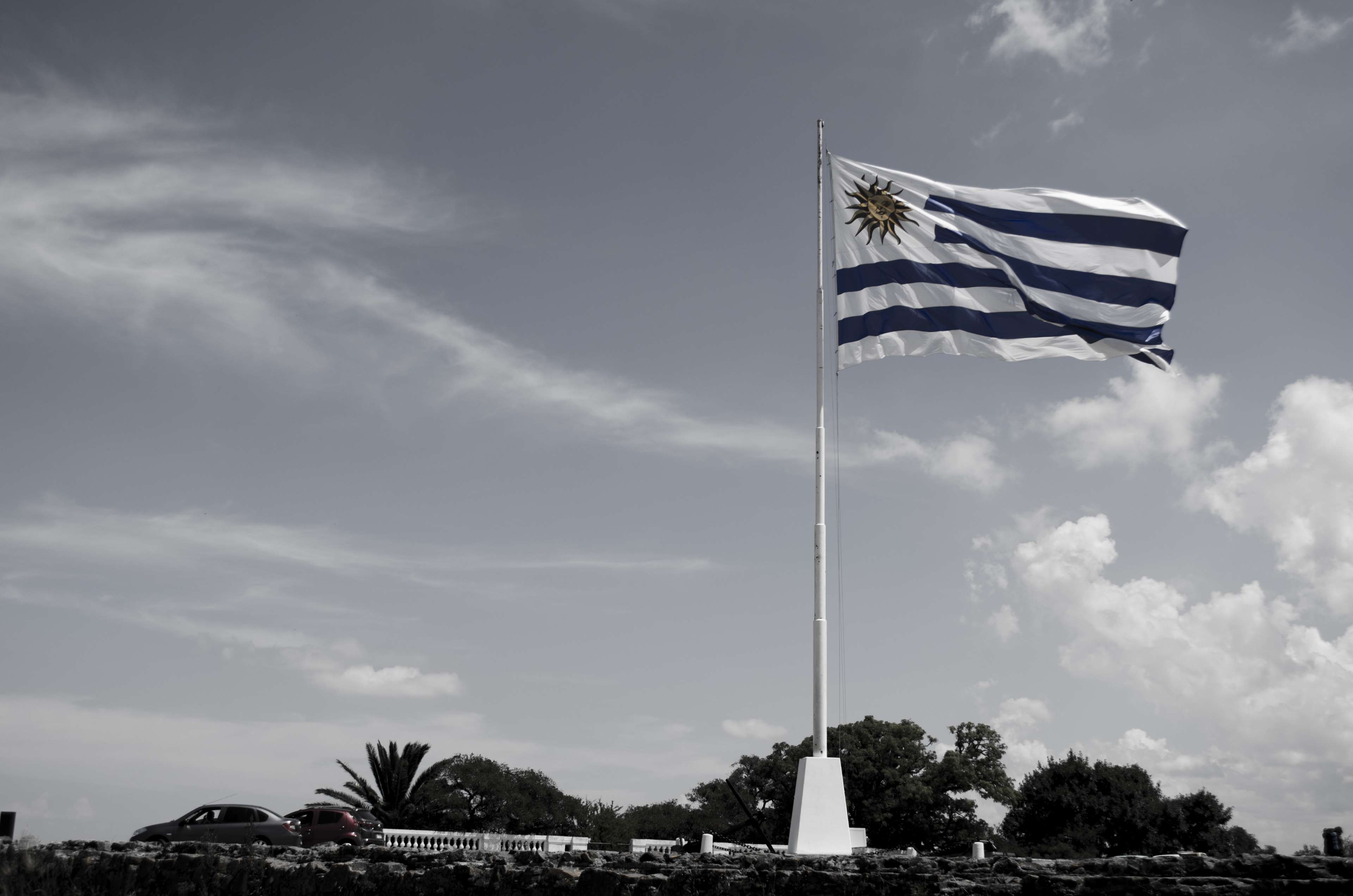 Uruguay flag on a flagpole under clouds HD Wallpaper