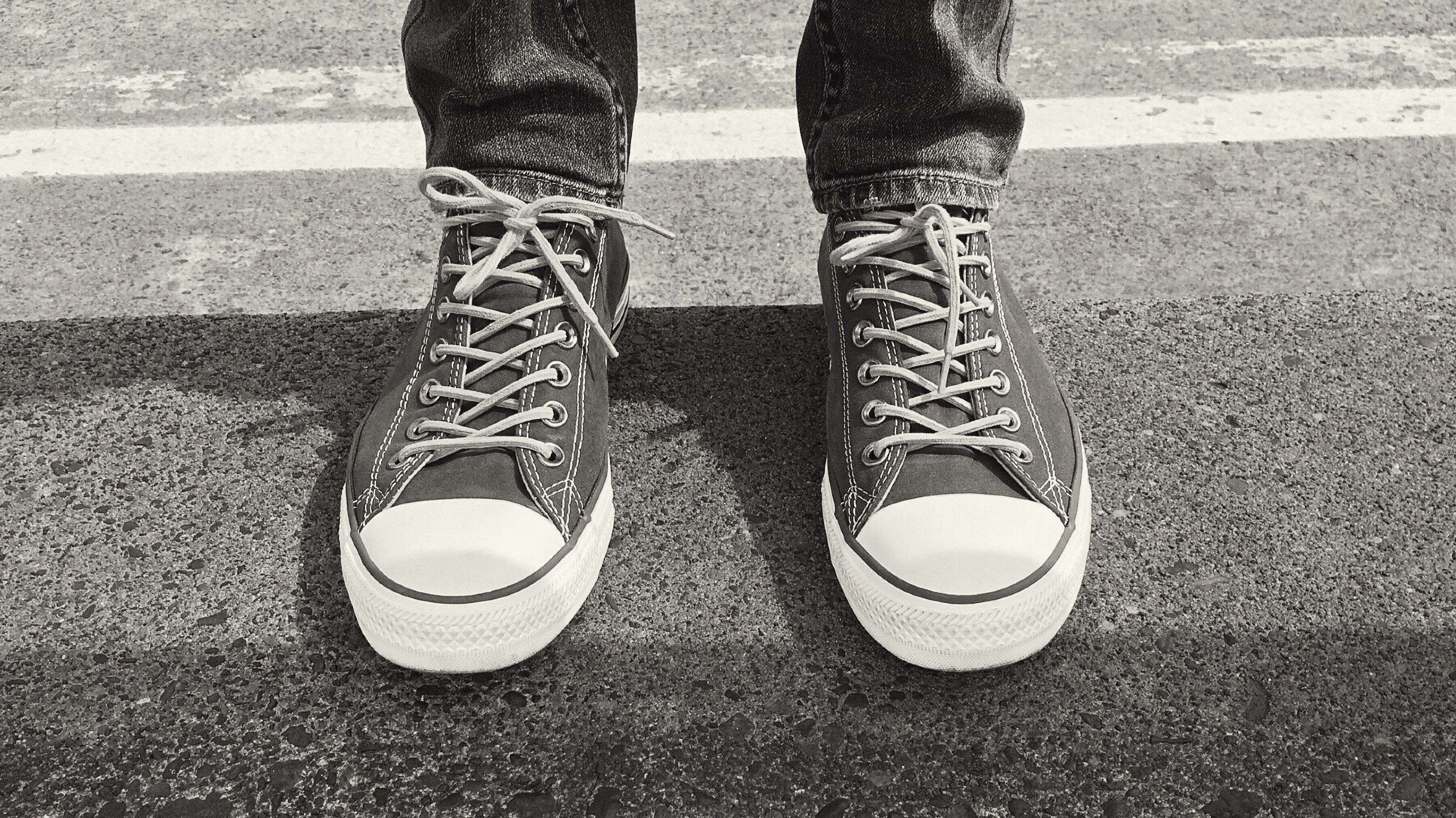 Person wearing black Converse sneakers on a street HD Wallpaper