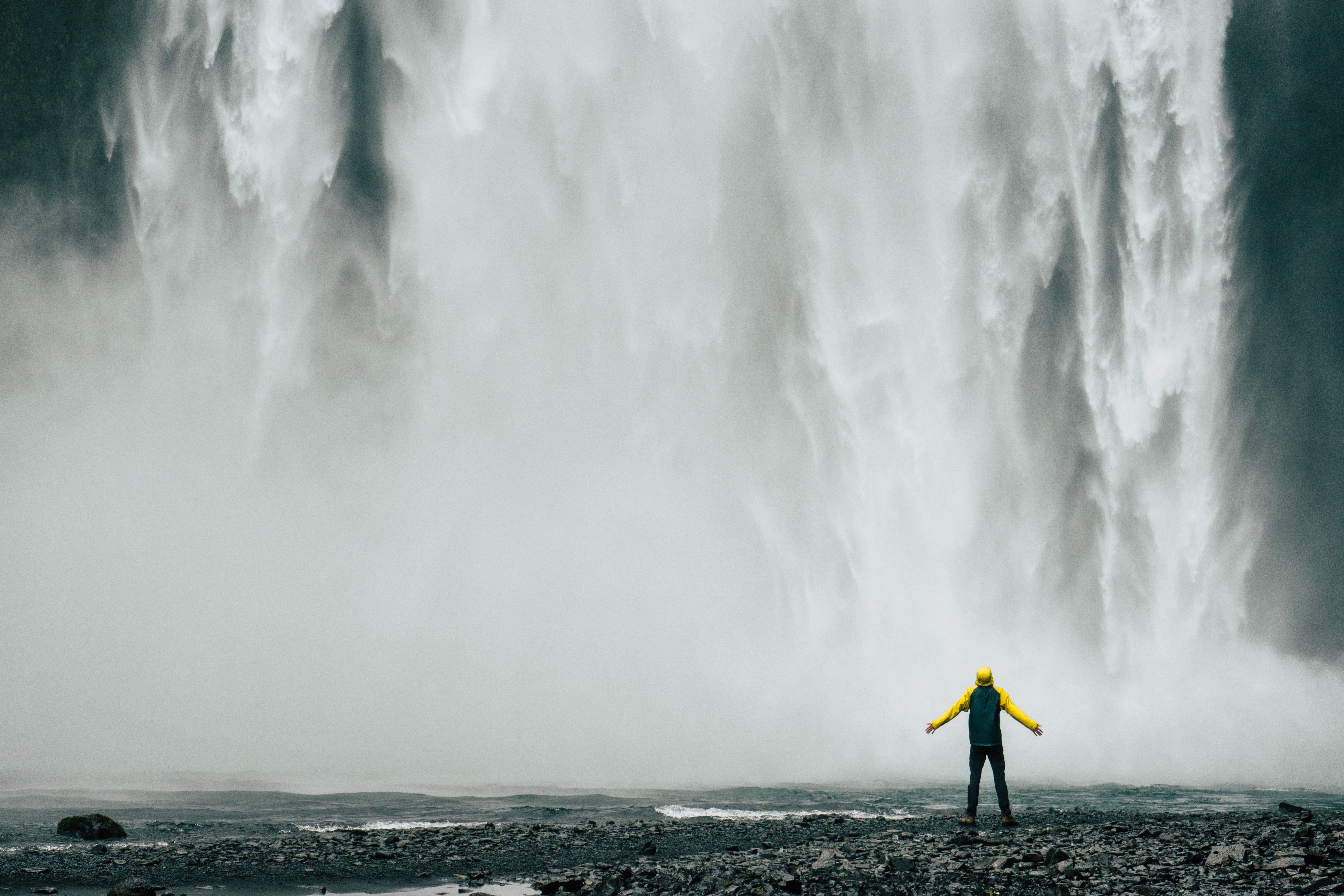 Person in yellow jacket at Skogafoss waterfall in Iceland HD Wallpaper