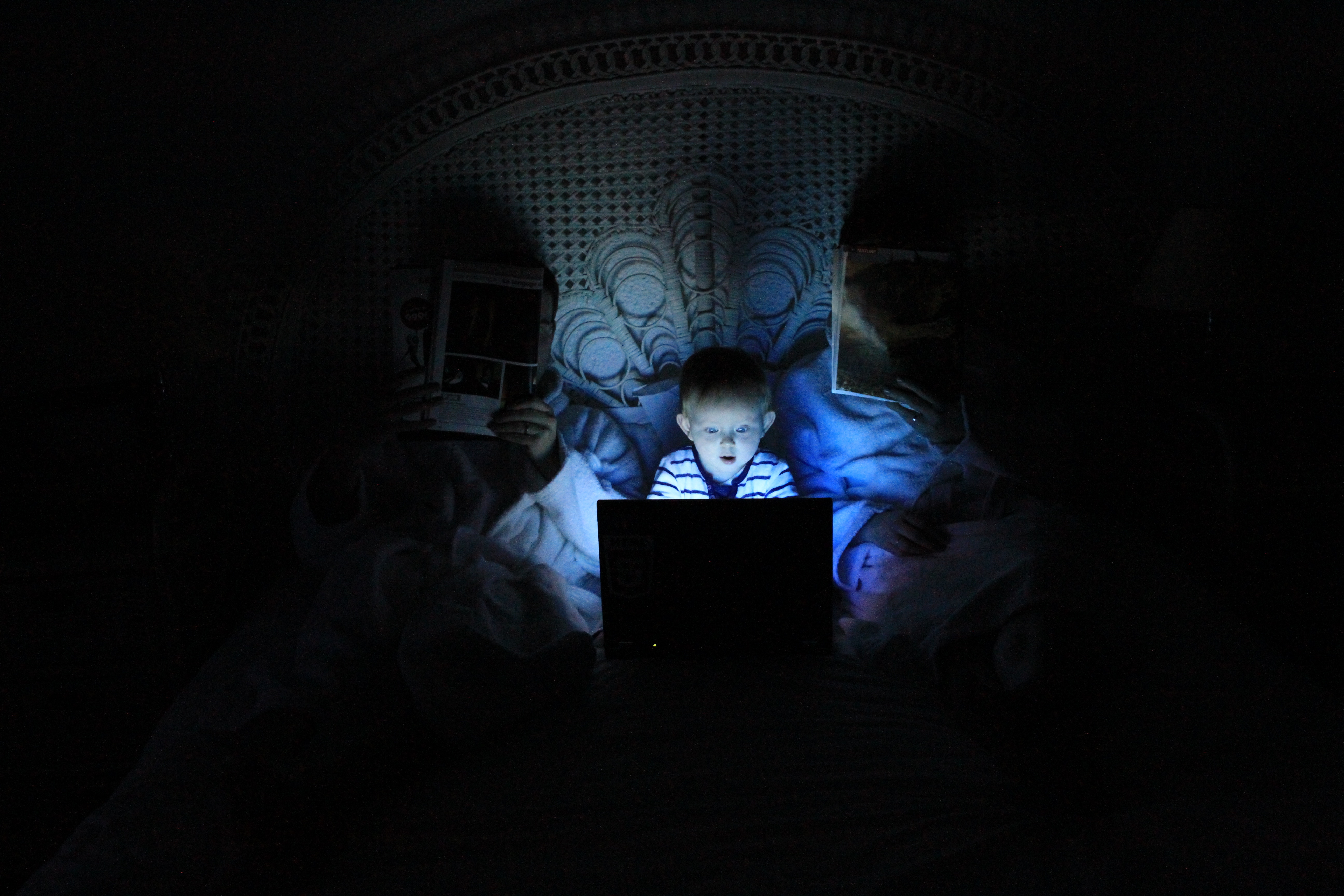 Child and parents looking at a laptop in bed at night HD Wallpaper