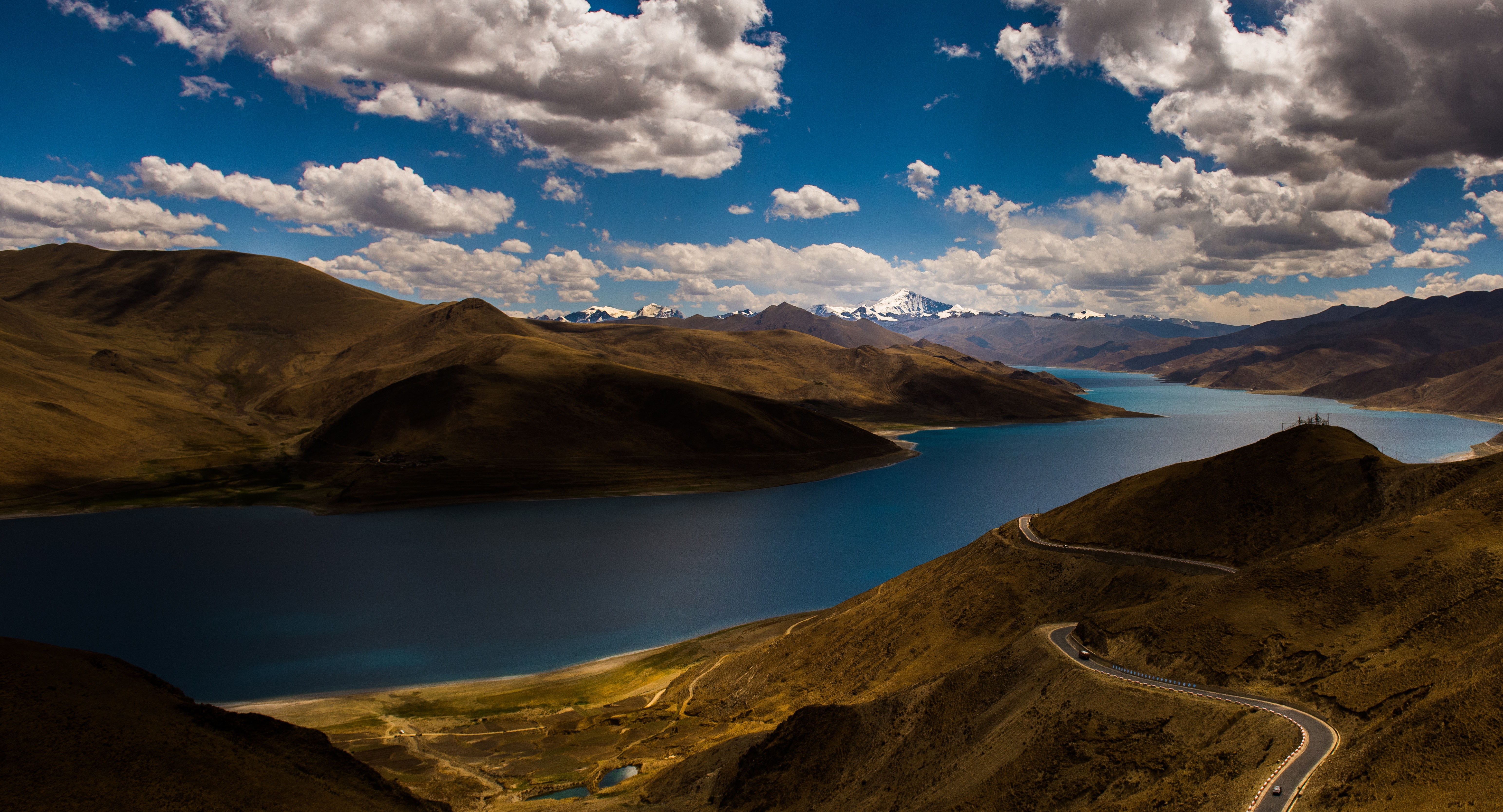 Winding road beside a blue lake and mountains HD Wallpaper