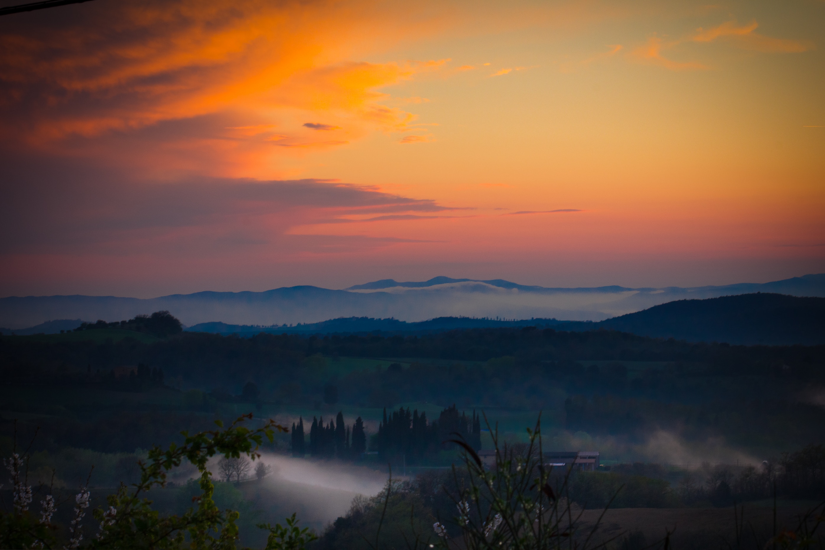 Misty rolling hills at sunset with orange sky HD Wallpaper