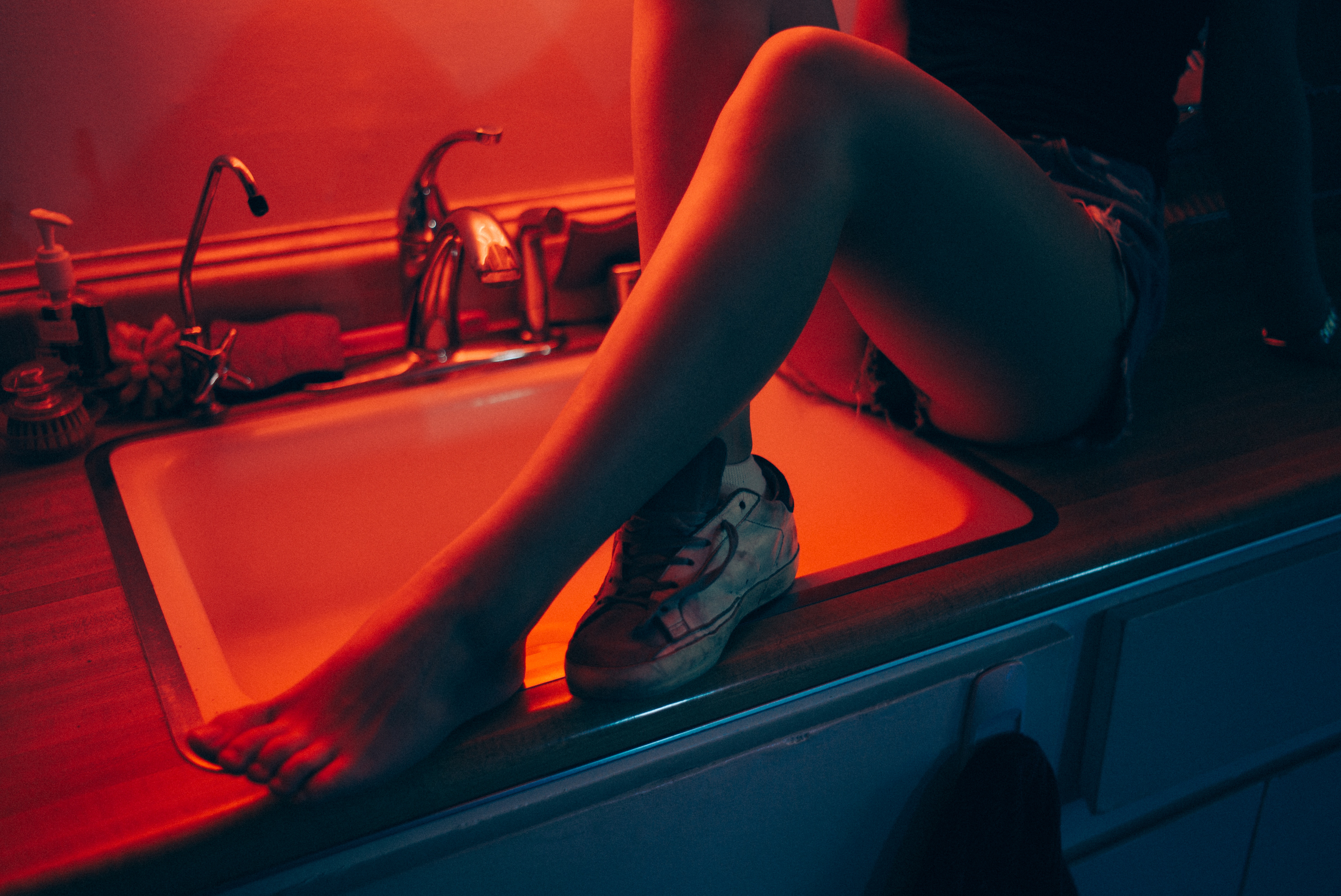 Woman sitting on a kitchen counter with a shoe on her foot HD Wallpaper