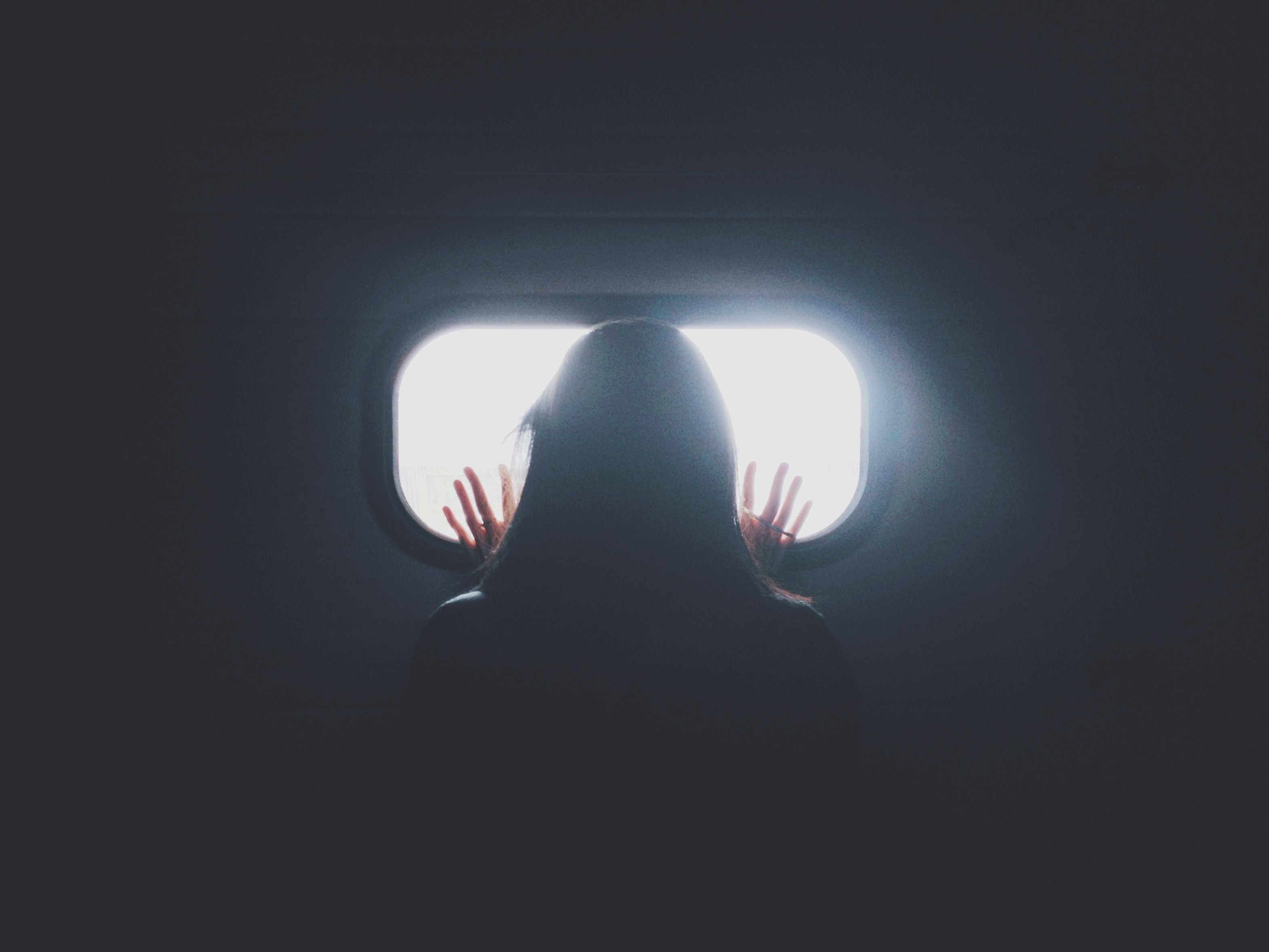 Silhouette of a woman looking out an airplane window HD Wallpaper
