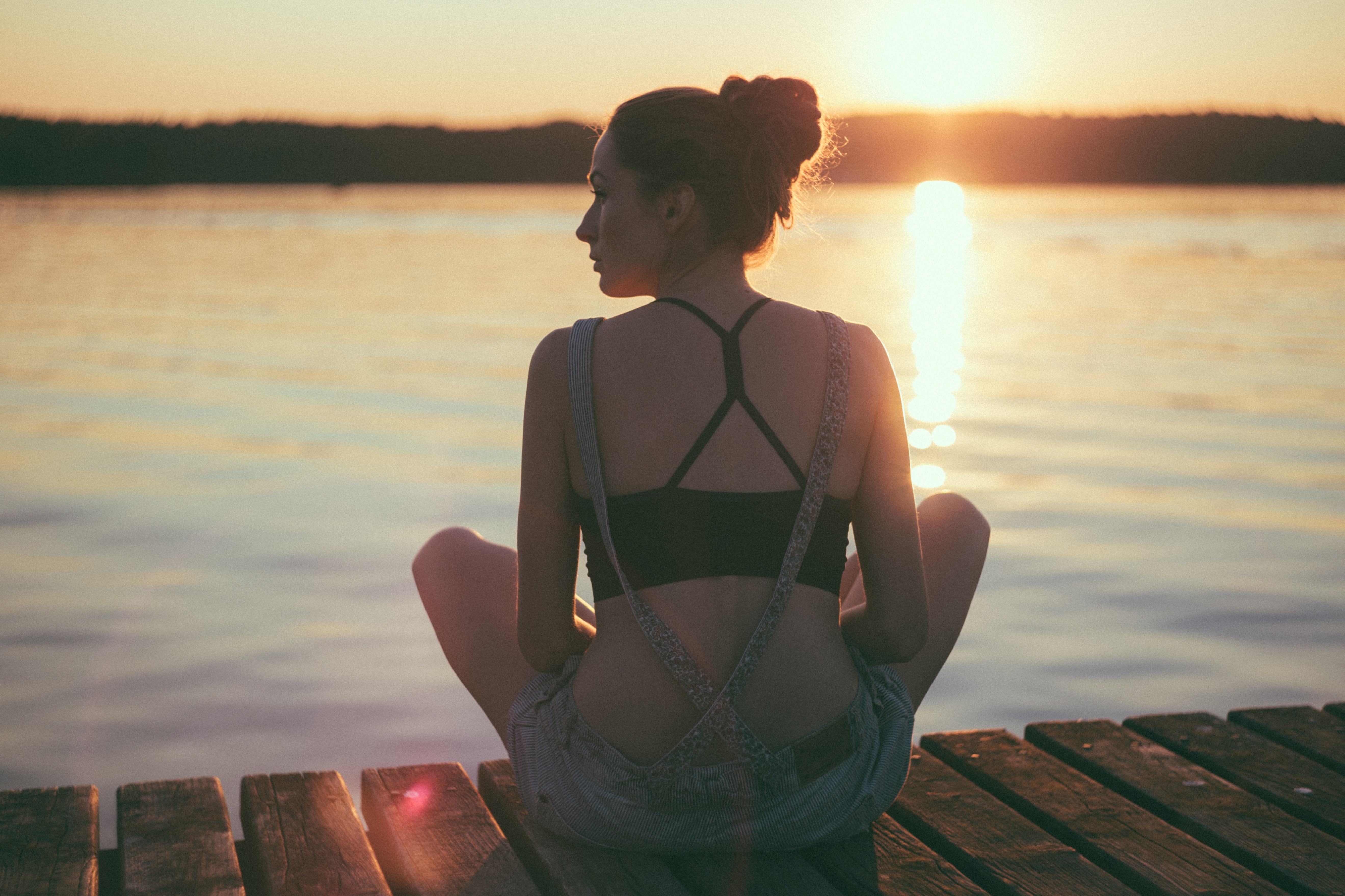 Woman sitting on a dock at sunset HD Wallpaper