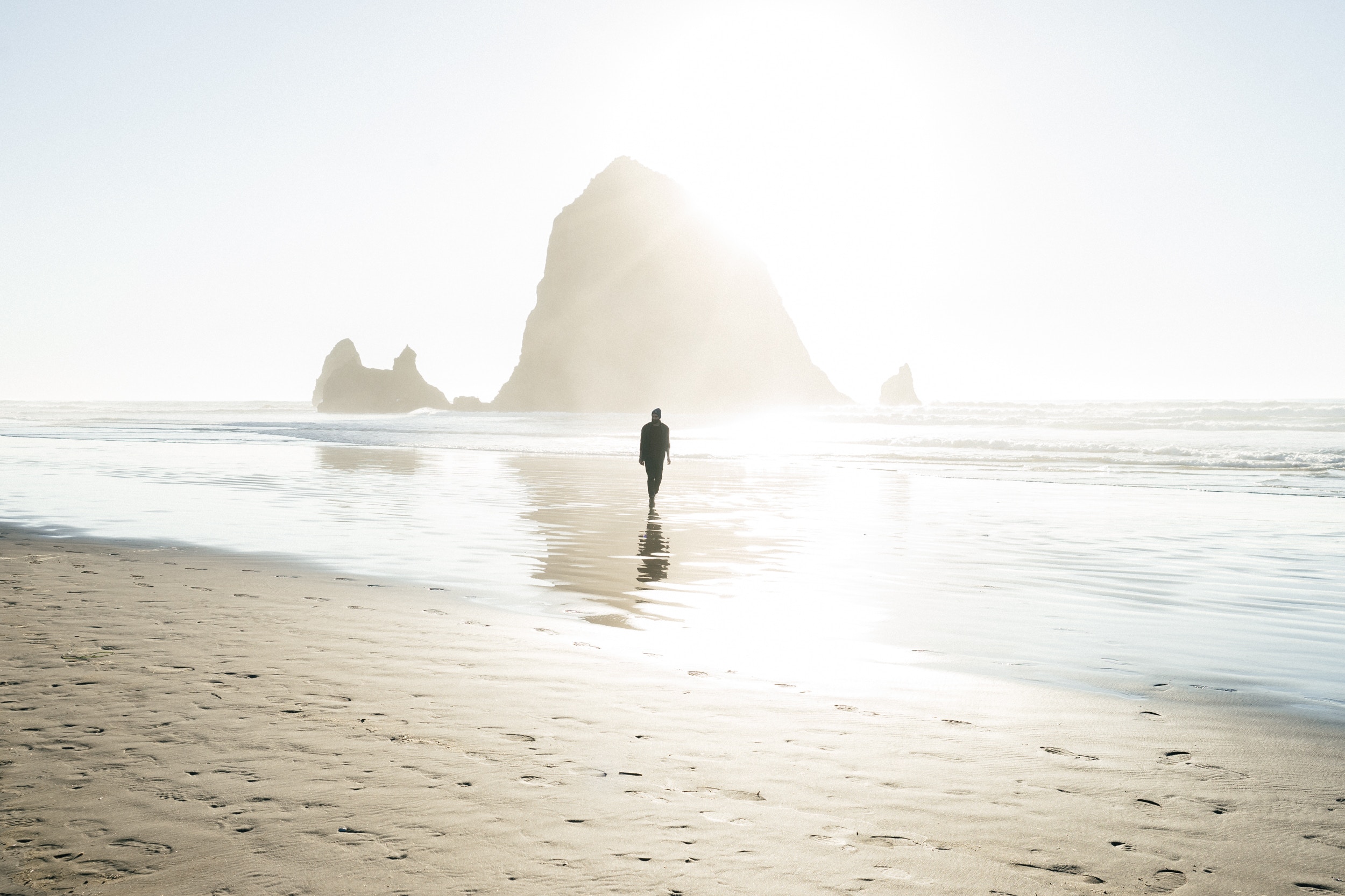 Man walking on Cannon Beach with Haystack Rock HD Wallpaper