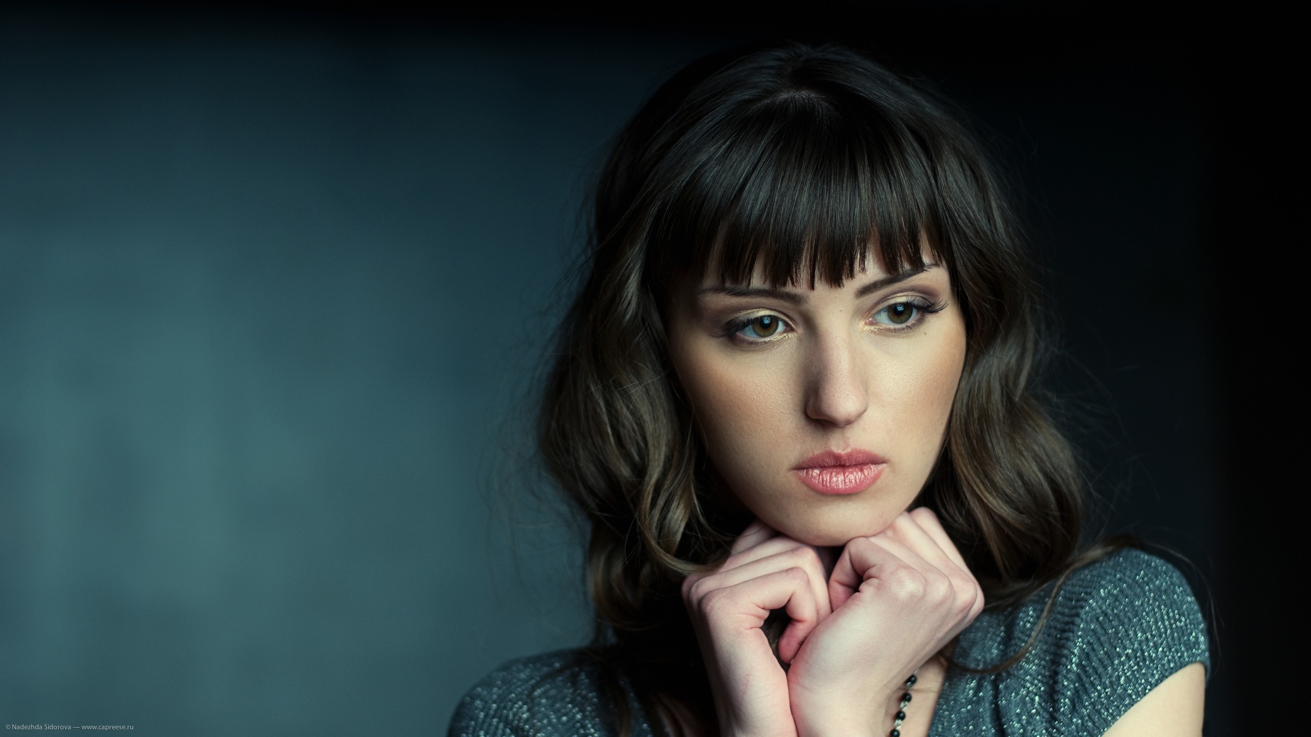 Woman with bangs looking down thoughtfully HD Wallpaper