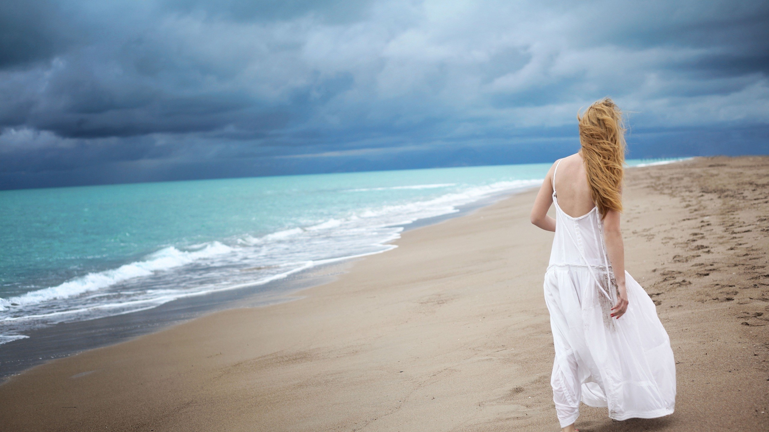 Woman in white dress walking on a beach HD Wallpaper