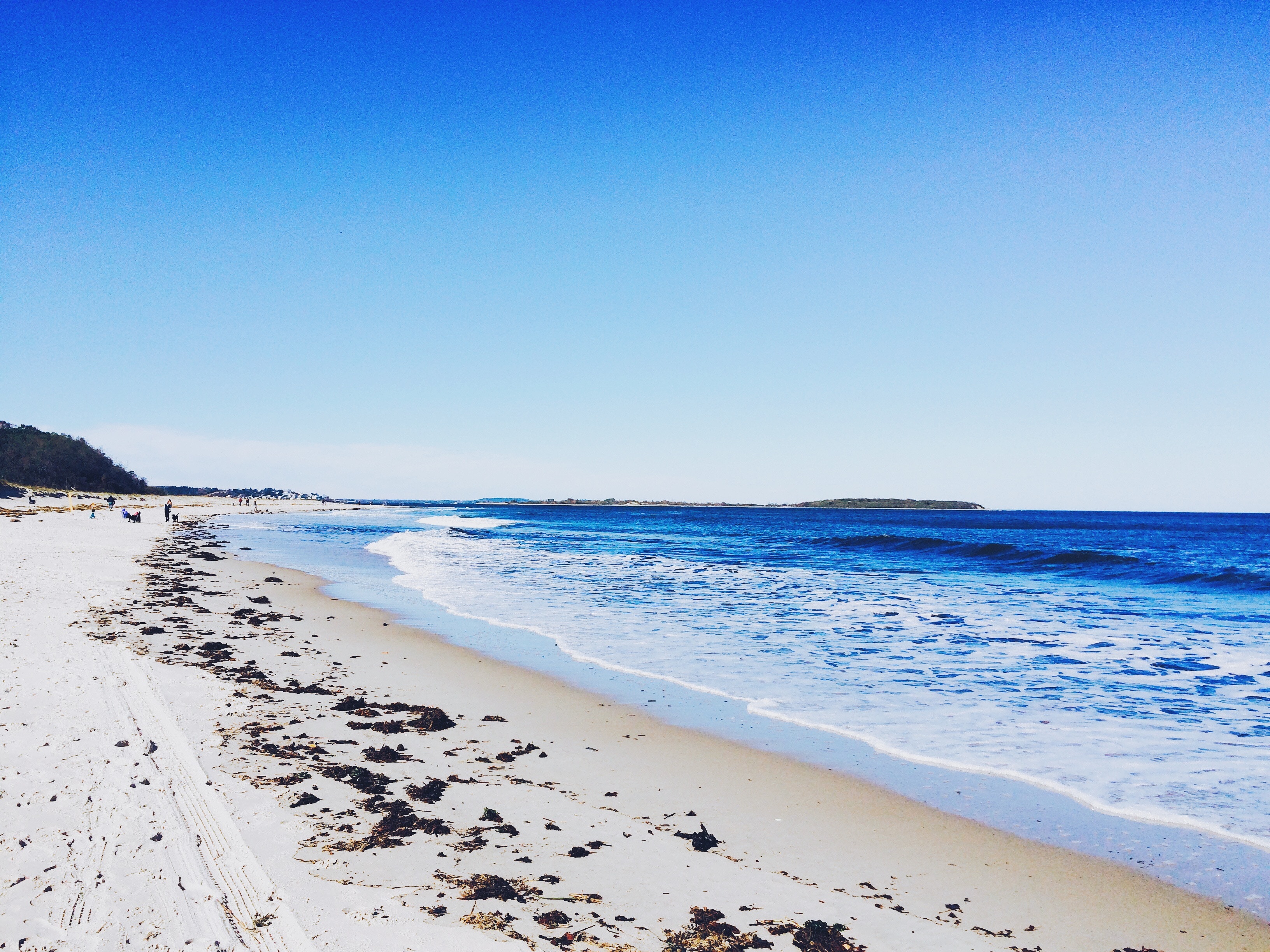 Sandy beach with ocean waves and distant island HD Wallpaper