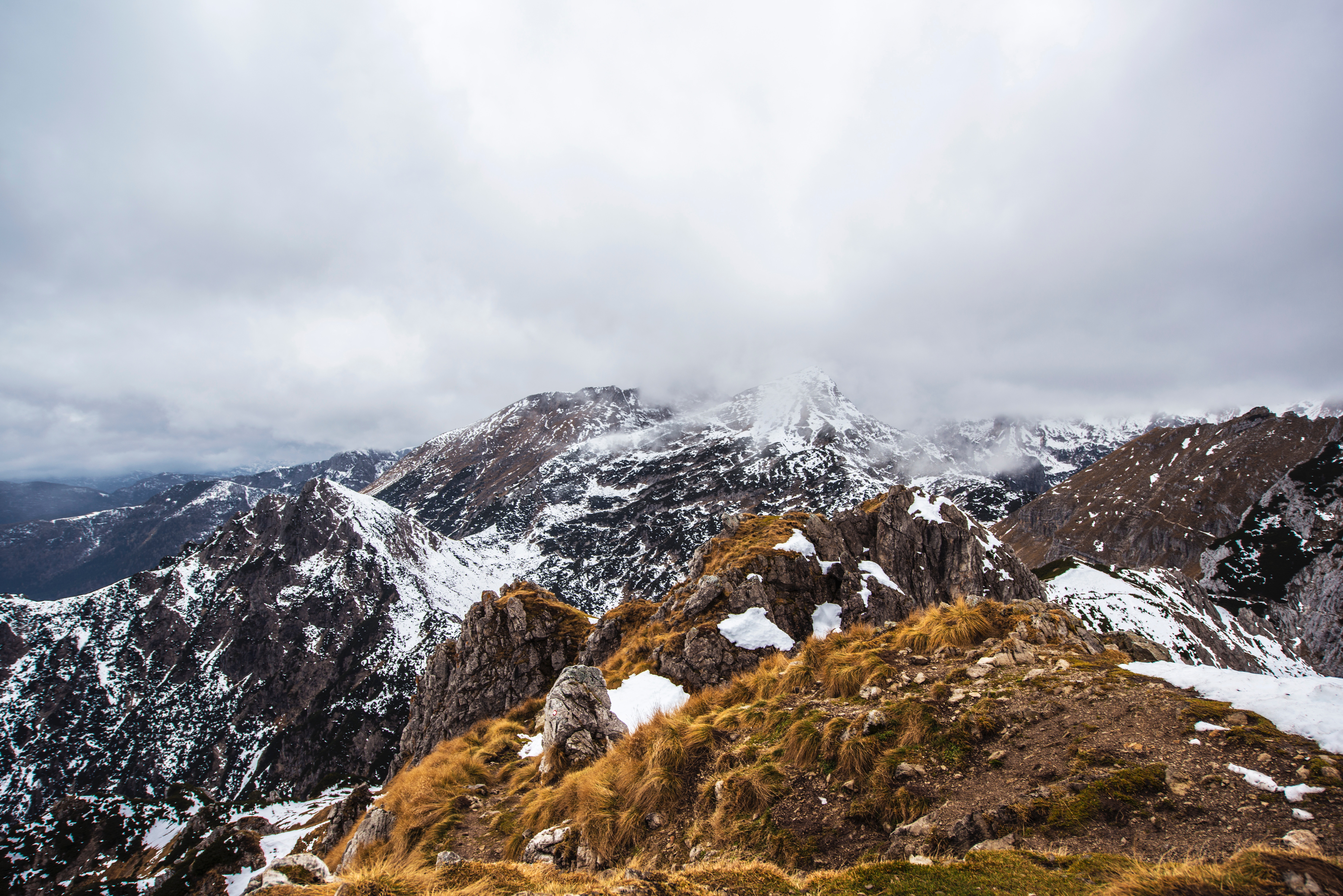 Snow-covered mountains under a cloudy sky HD Wallpaper