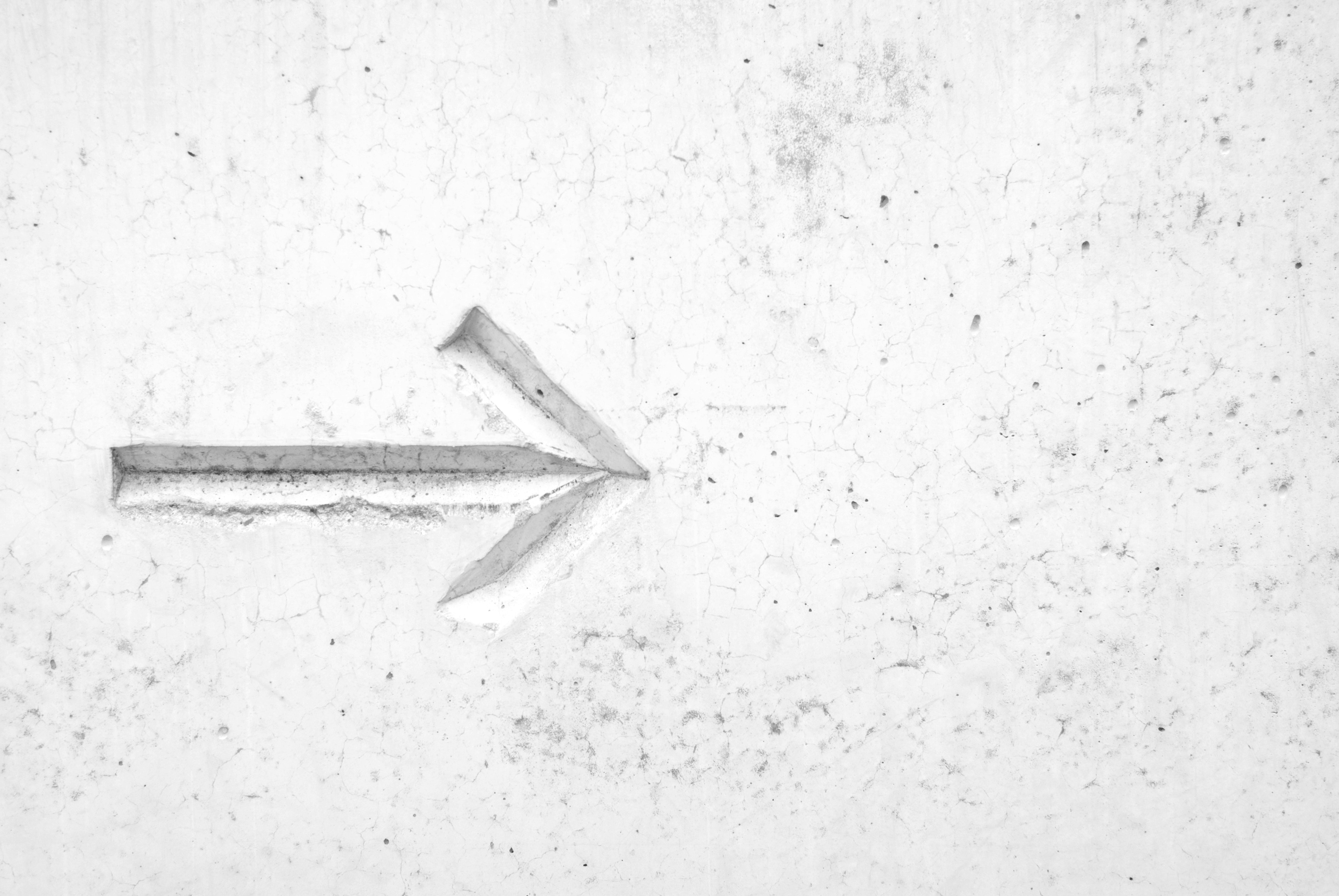 Carved arrow on a textured concrete wall HD Wallpaper