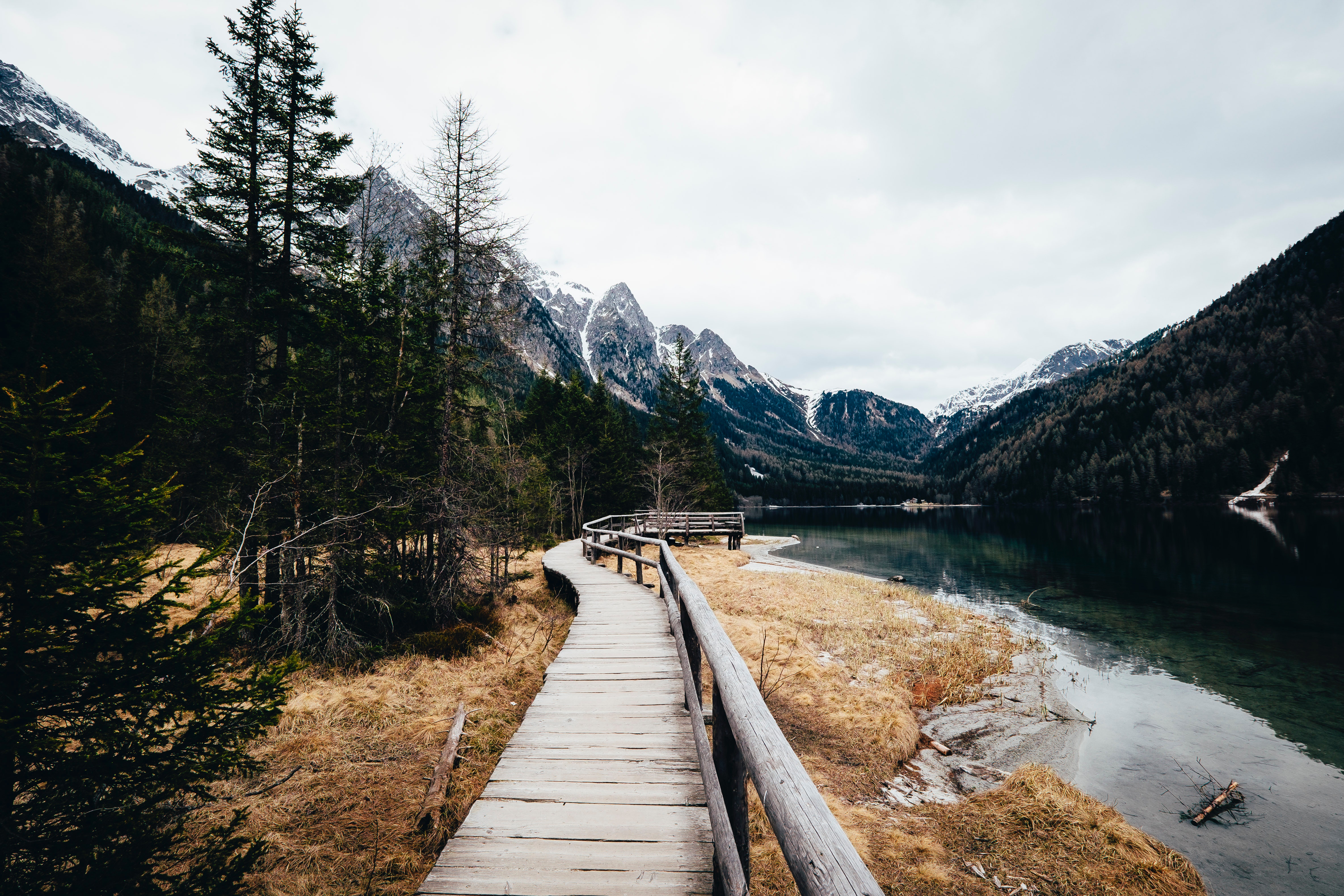 Wooden walkway along a lake with mountains HD Wallpaper