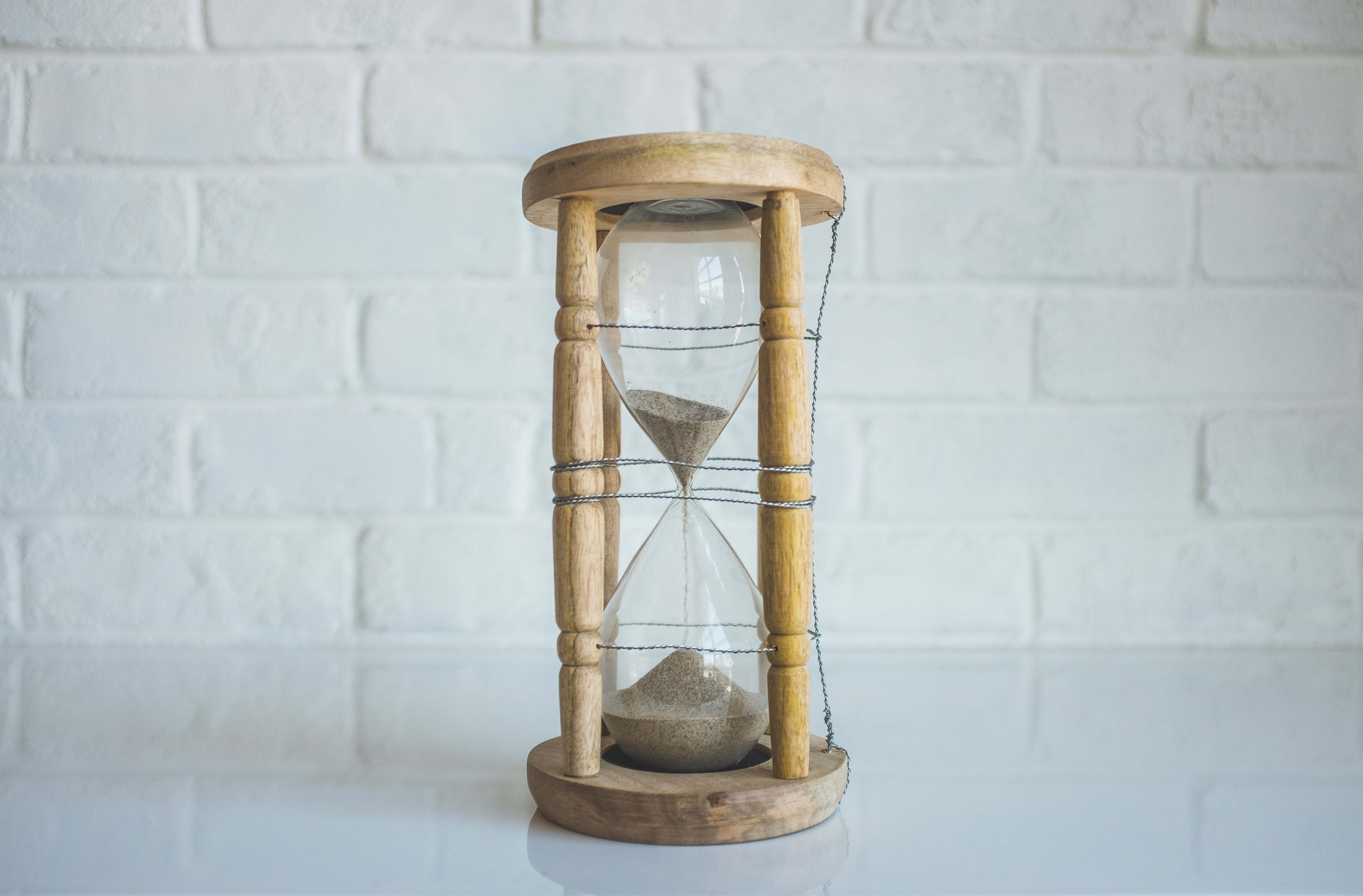 Wooden hourglass with sand on a white surface HD Wallpaper