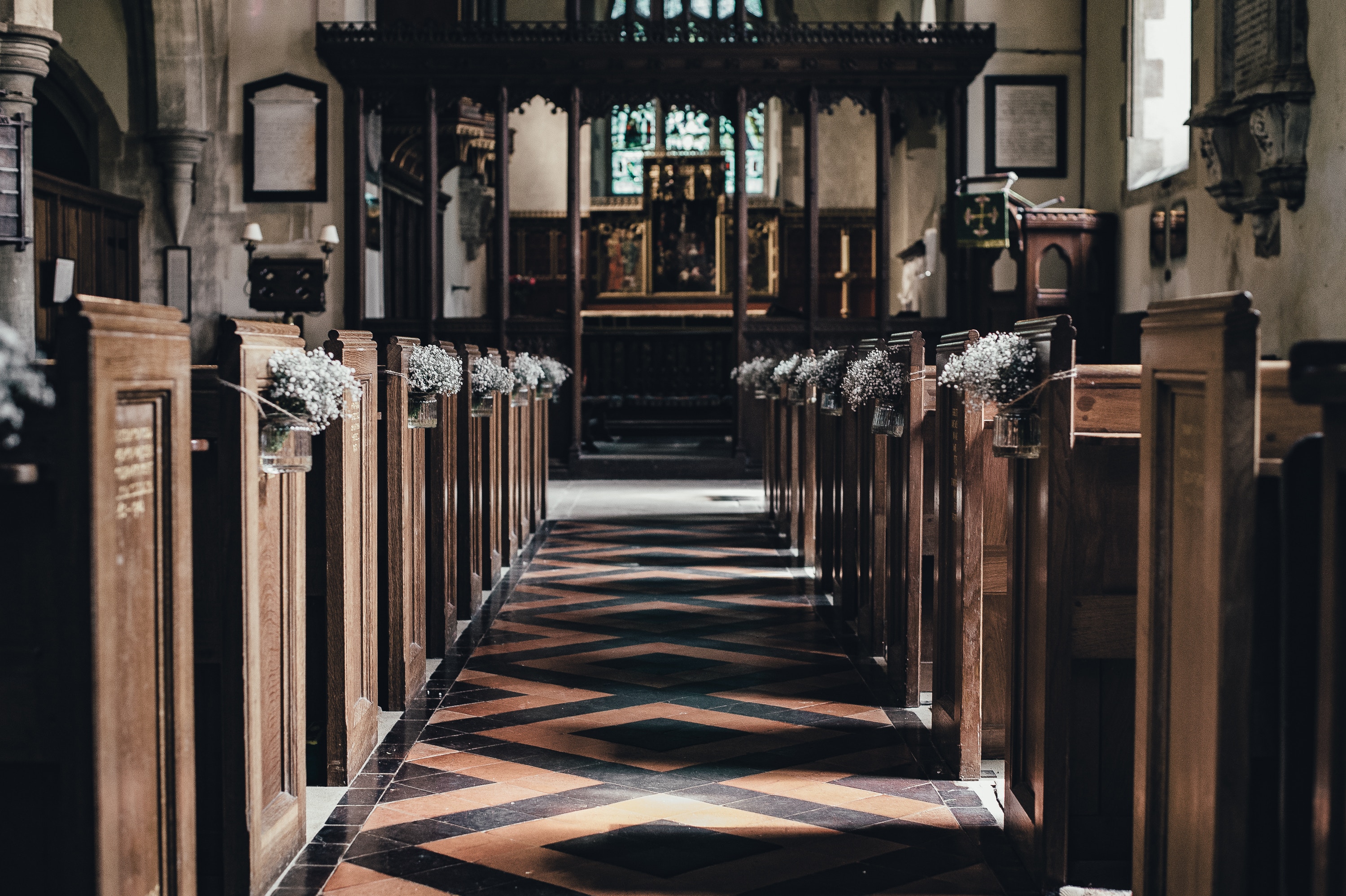 Church aisle with wooden pews and floral decorations HD Wallpaper