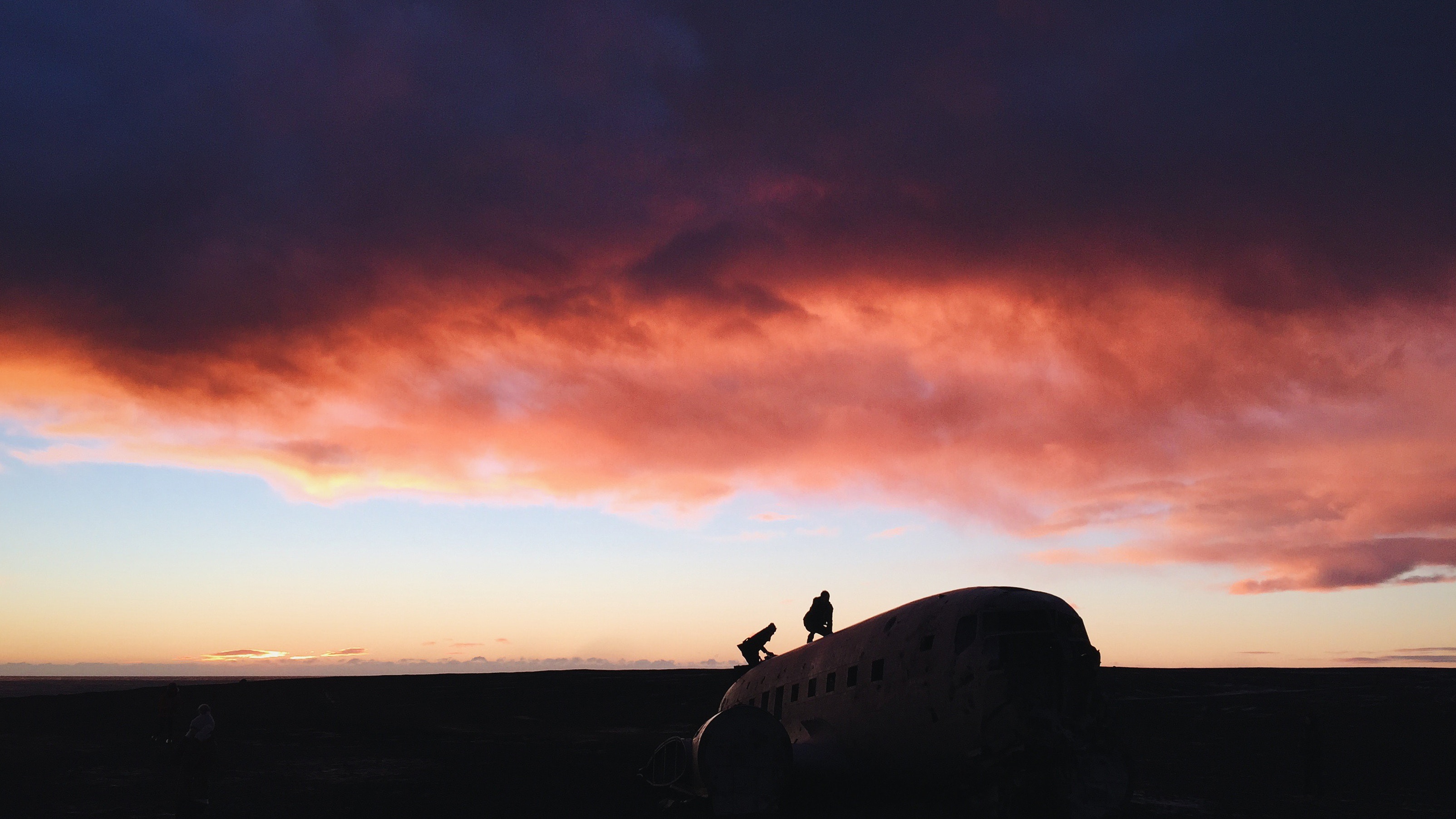 Silhouettes on a crashed plane at sunset in Iceland HD Wallpaper