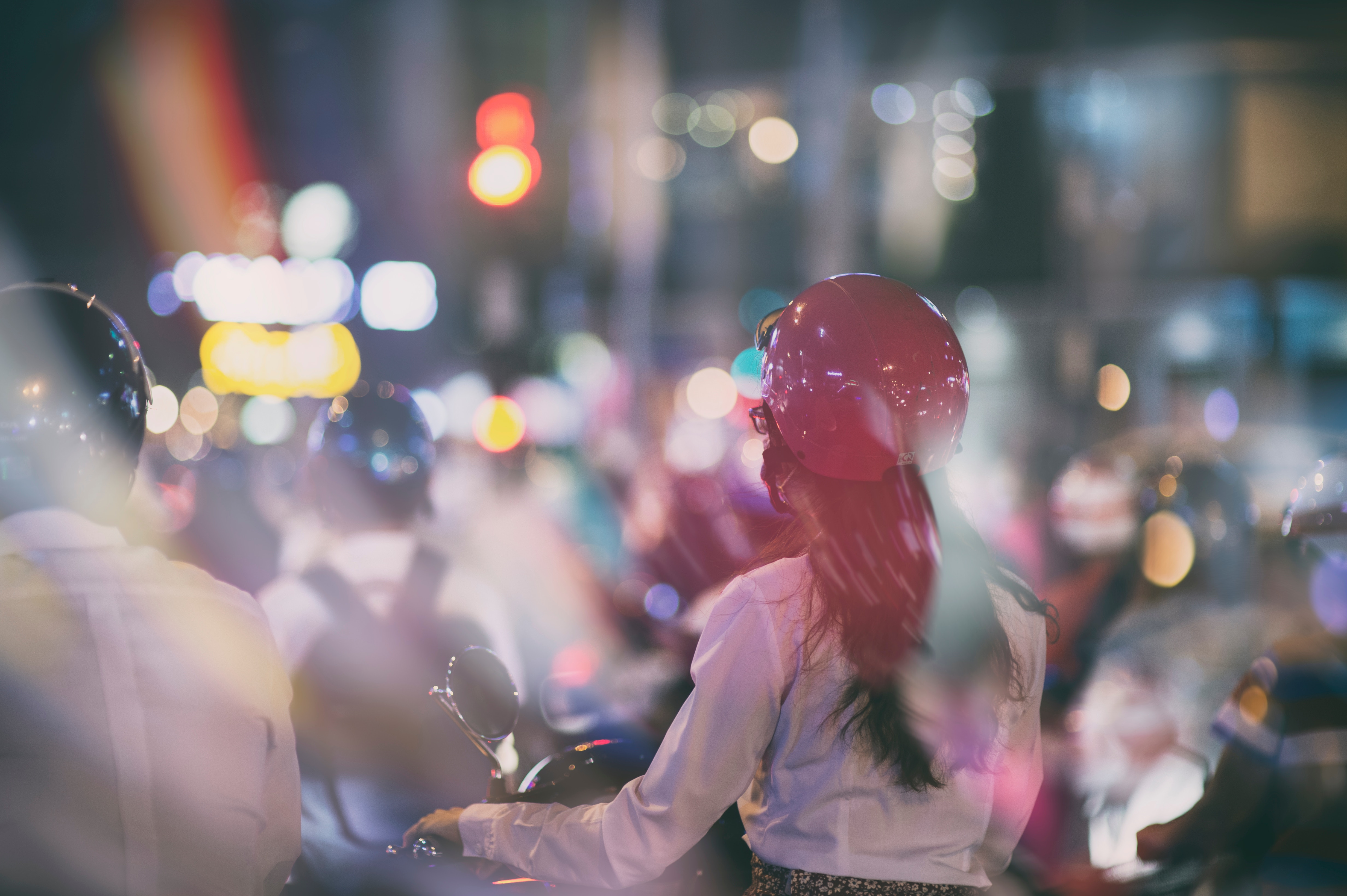 Woman in red helmet on a motorbike in city traffic at night HD Wallpaper