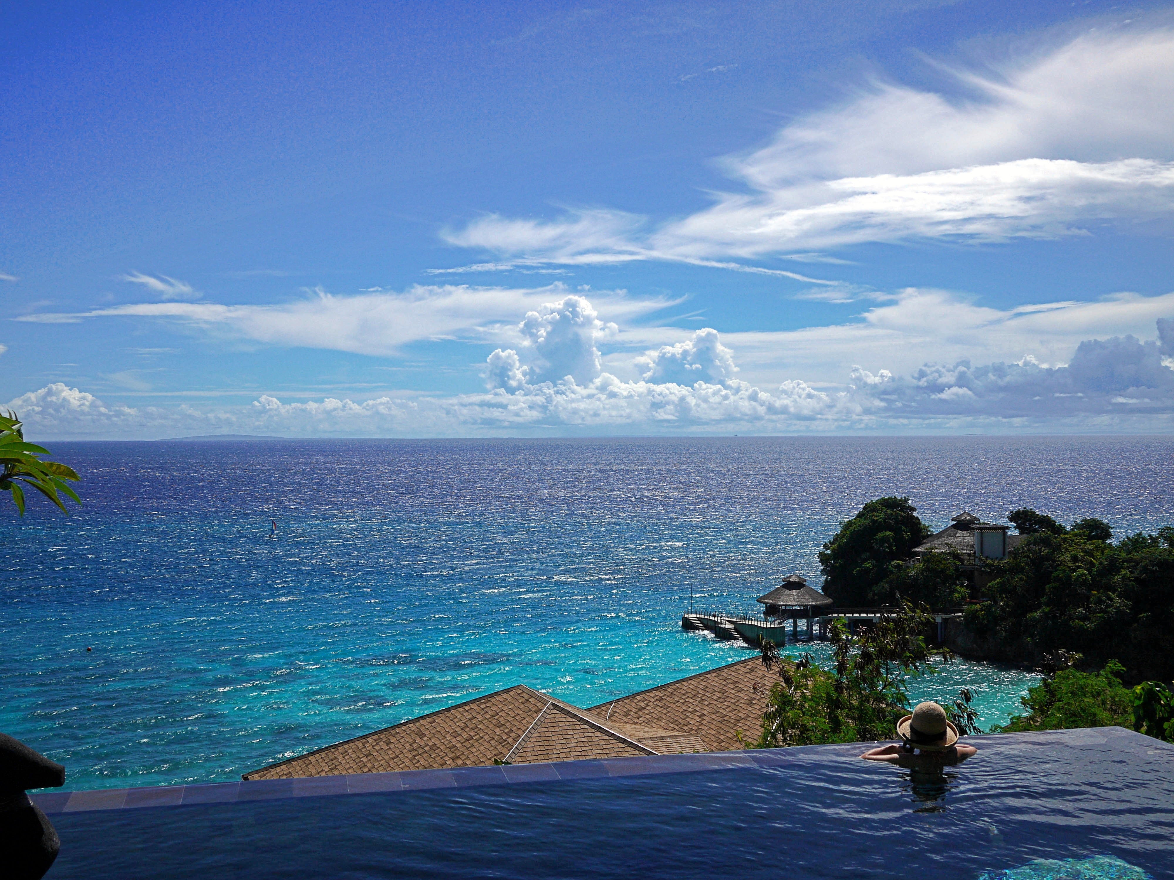Woman in pool overlooking tropical ocean view HD Wallpaper