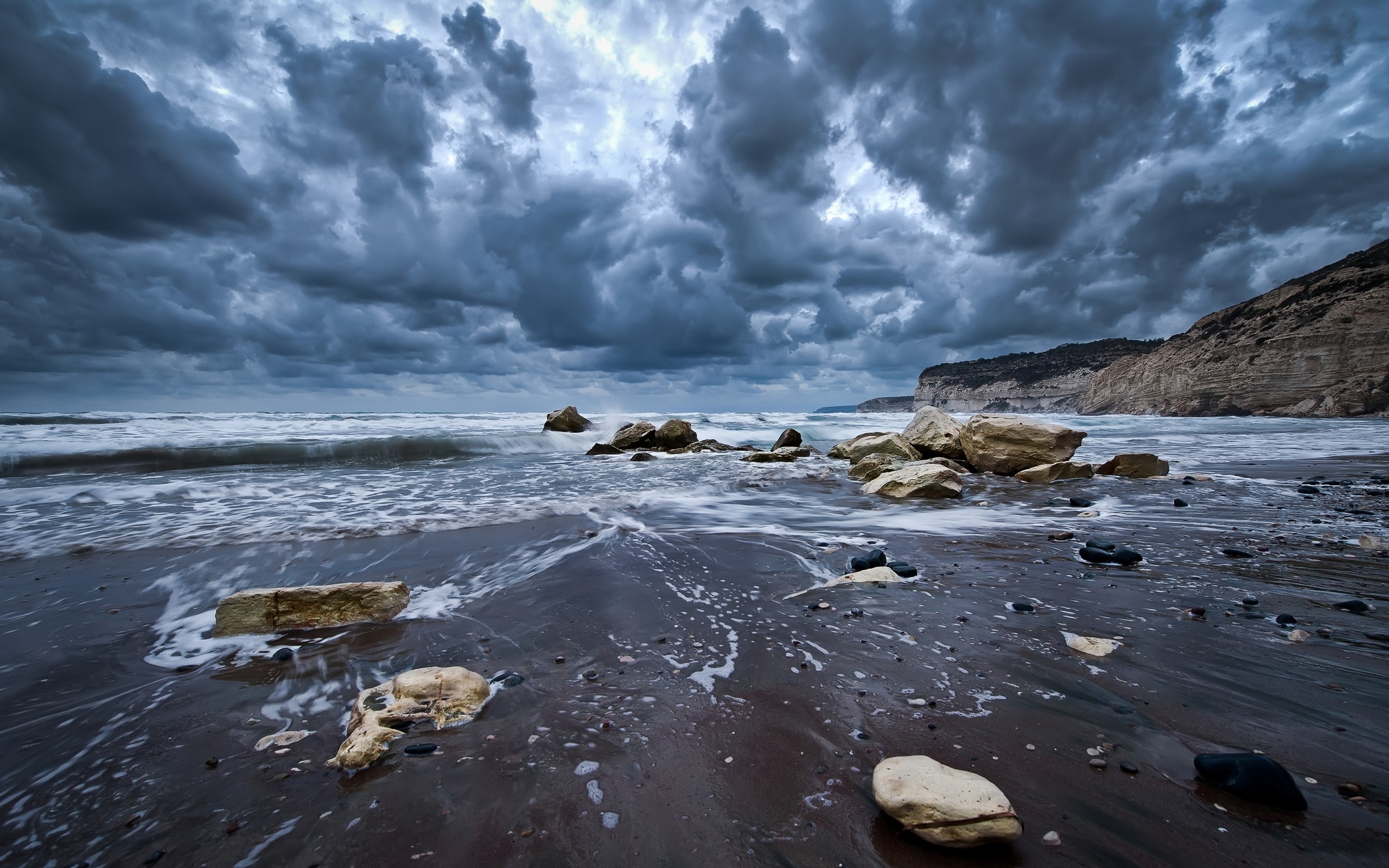 Gloomy beach with stormy clouds and waves crashing on rocks HD Wallpaper