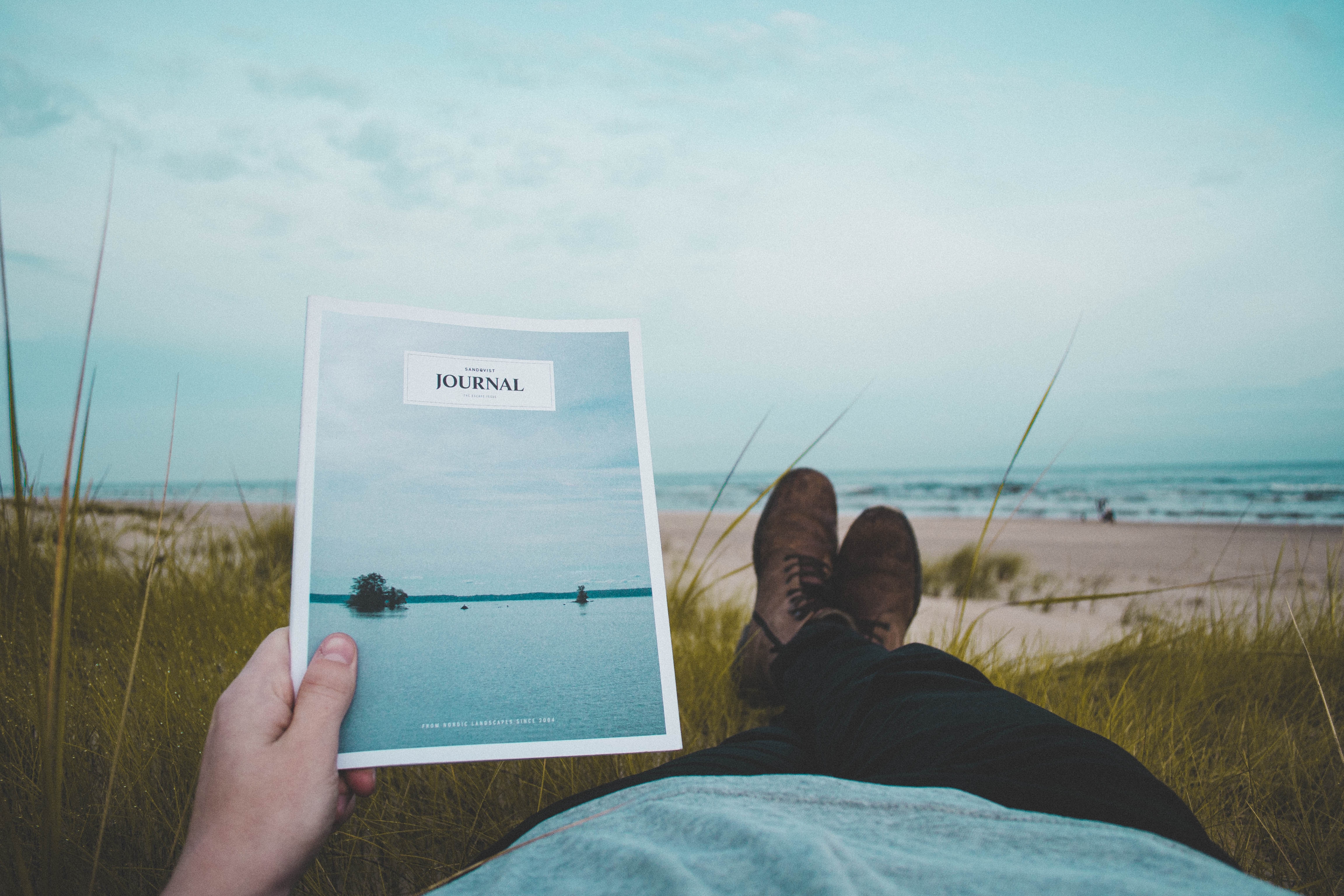 Person reading a journal on the beach HD Wallpaper