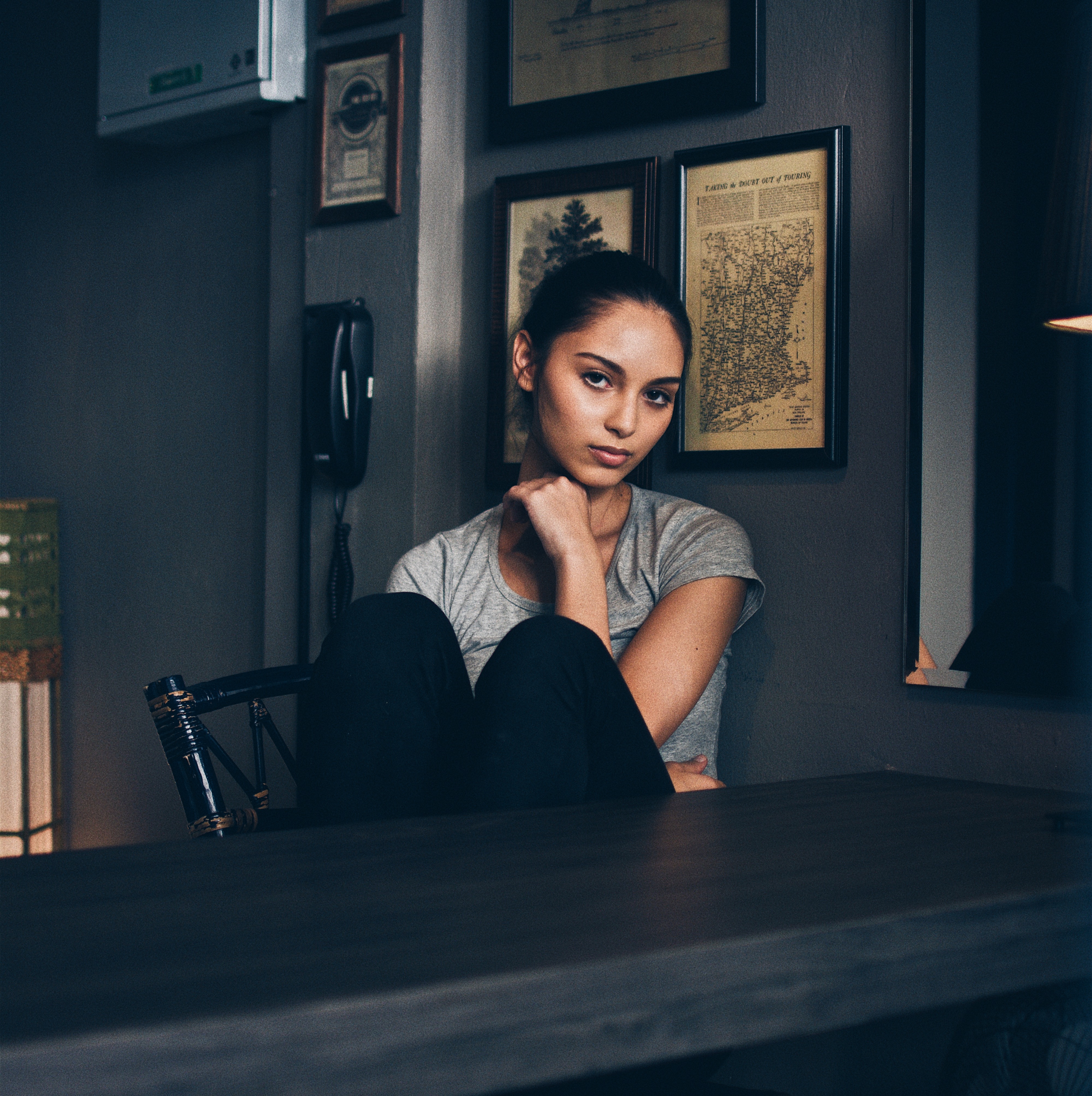 Woman sitting at a table with framed art on the wall HD Wallpaper