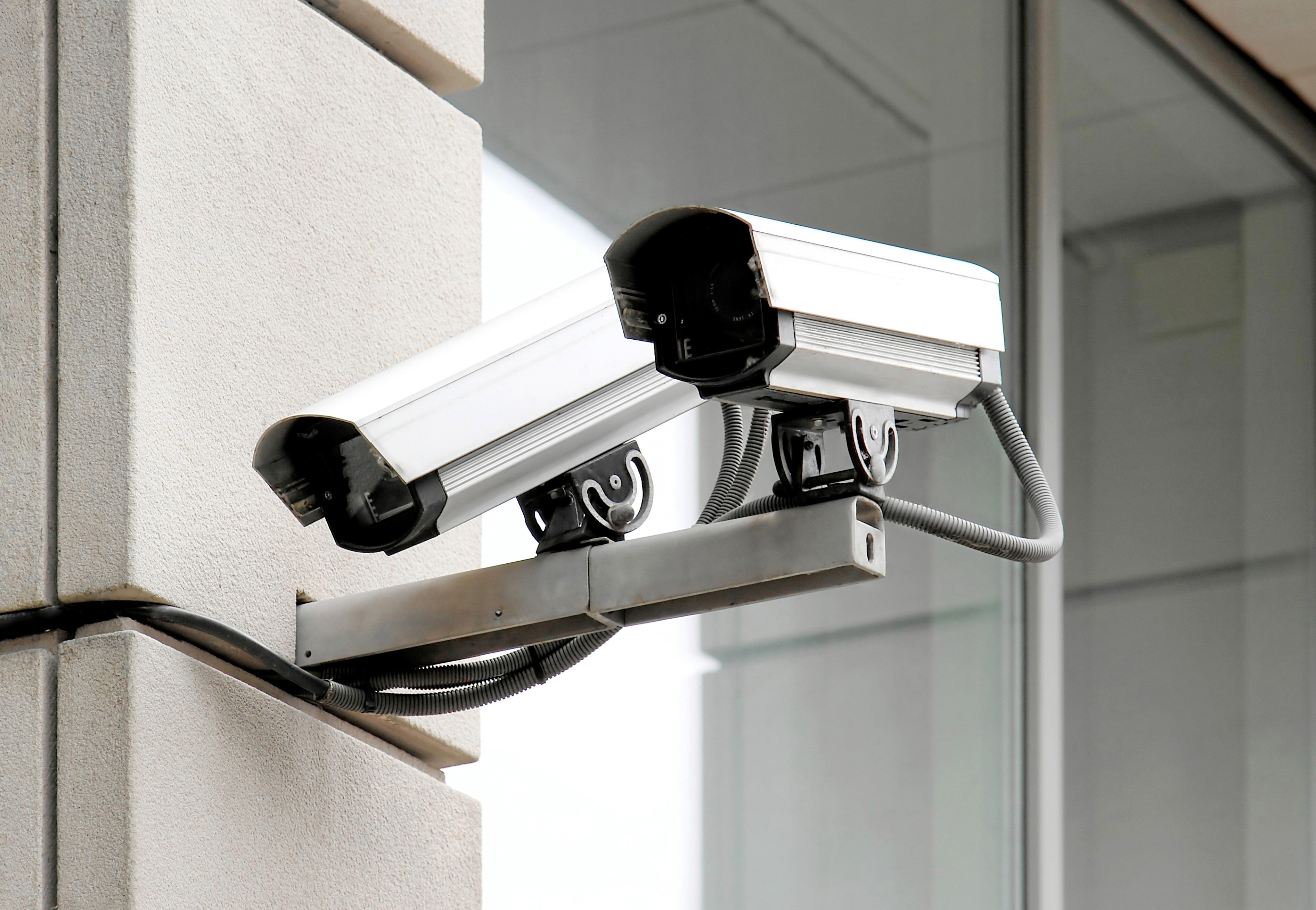Two surveillance cameras mounted on a building exterior HD Wallpaper