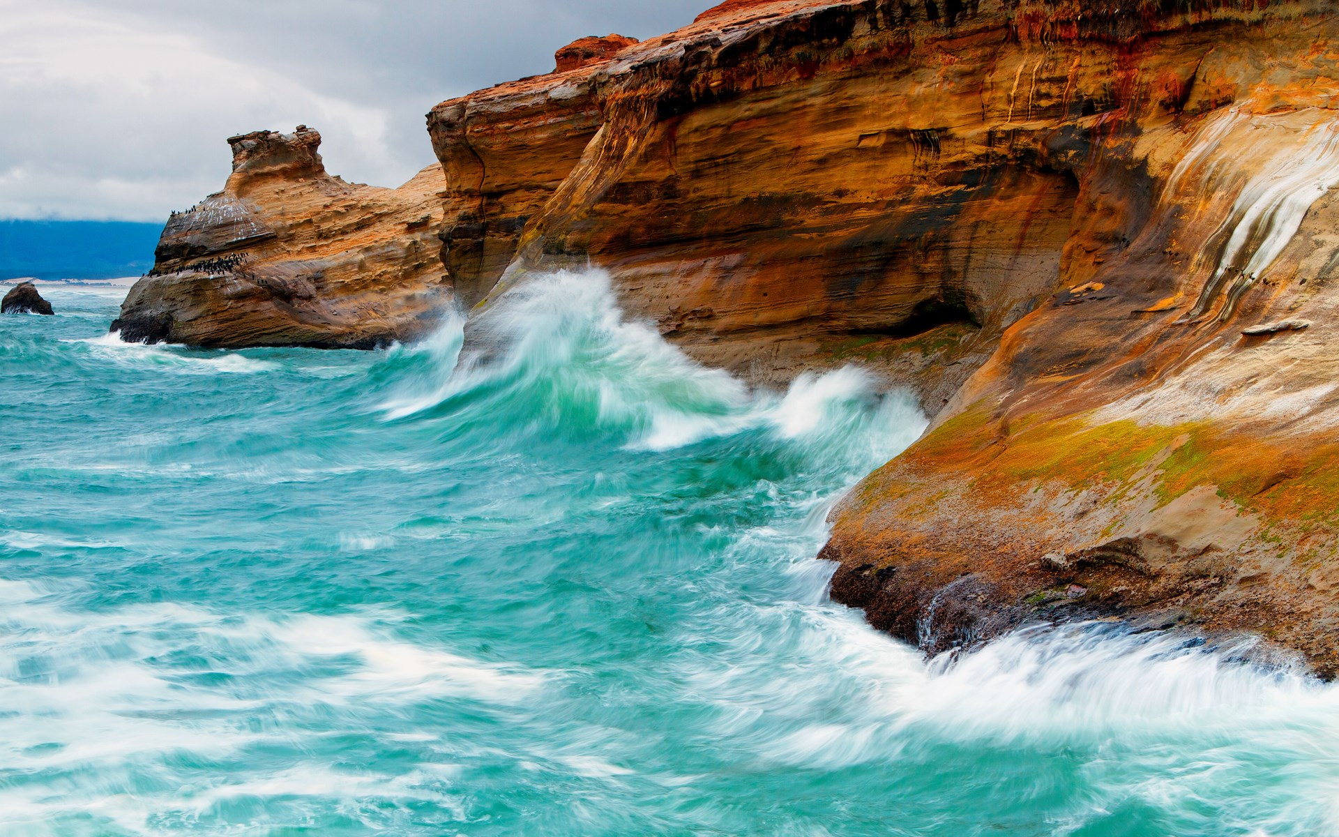 Waves crashing against rocky cliffs on a cloudy day HD Wallpaper