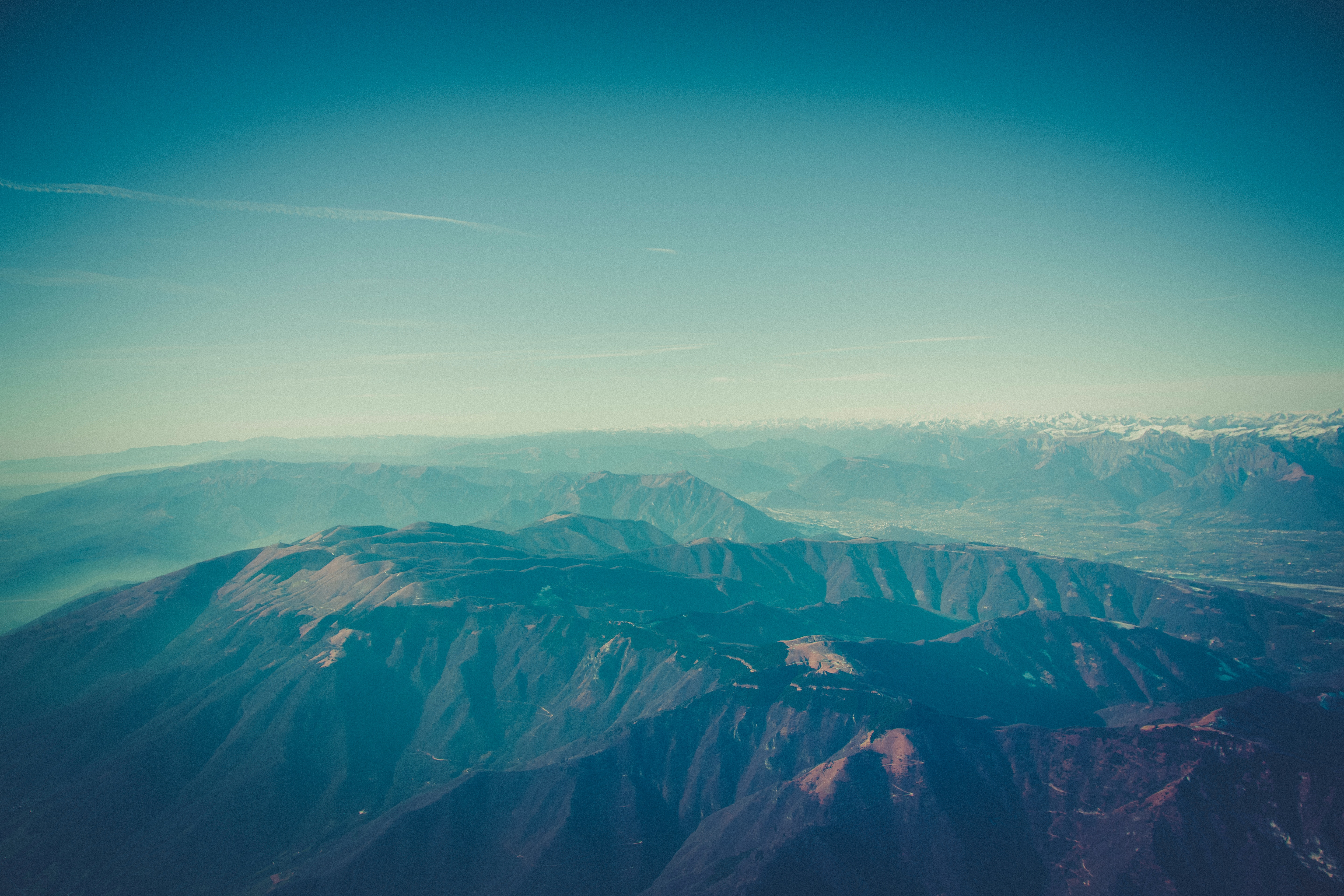 Aerial view of a vast mountain range under a hazy sky HD Wallpaper