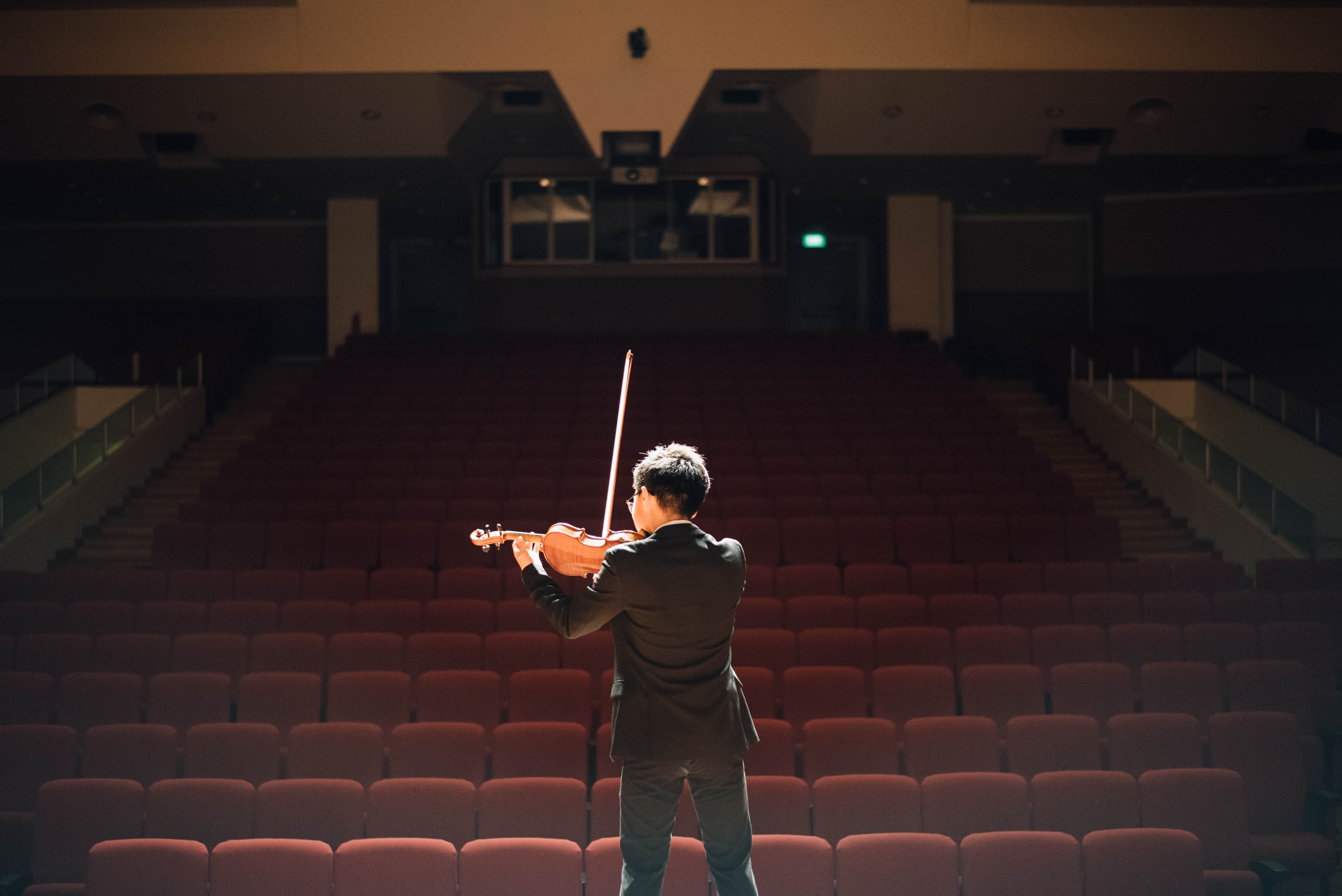Man playing violin in an empty auditorium HD Wallpaper