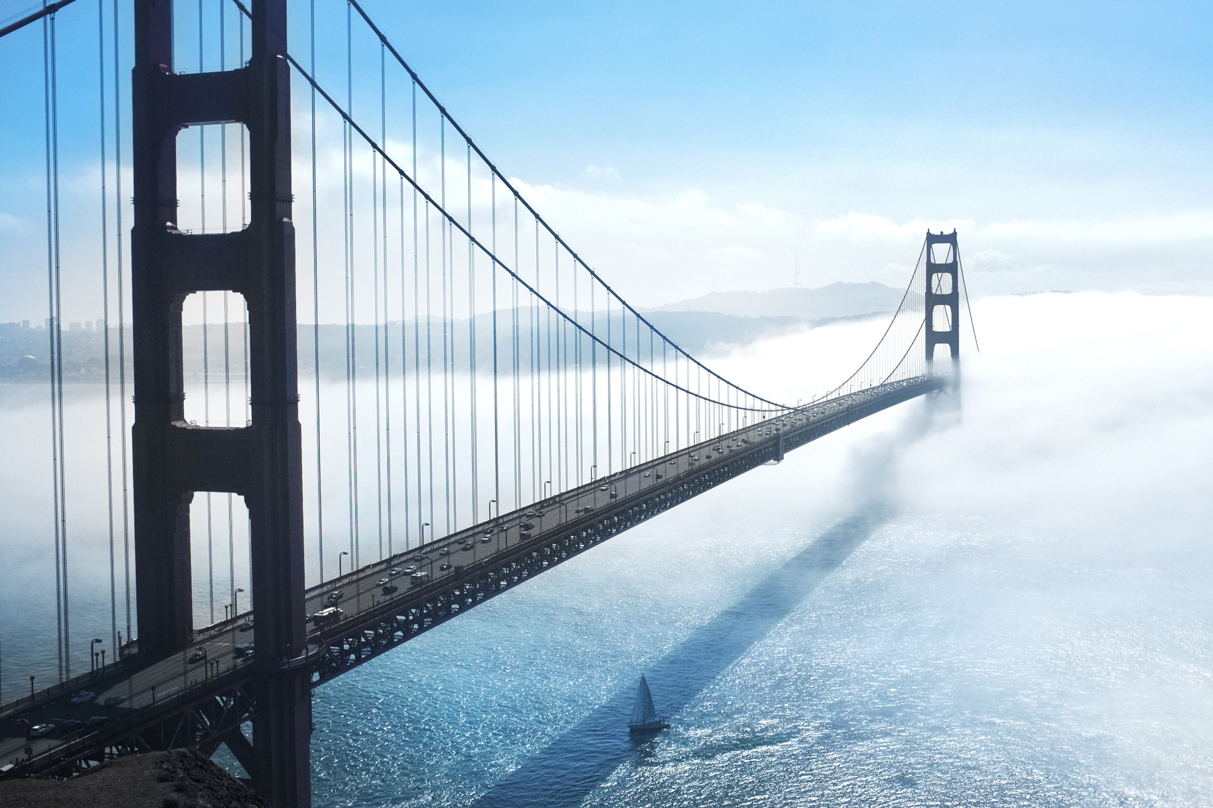 Golden Gate Bridge shrouded in fog with a sailboat HD Wallpaper
