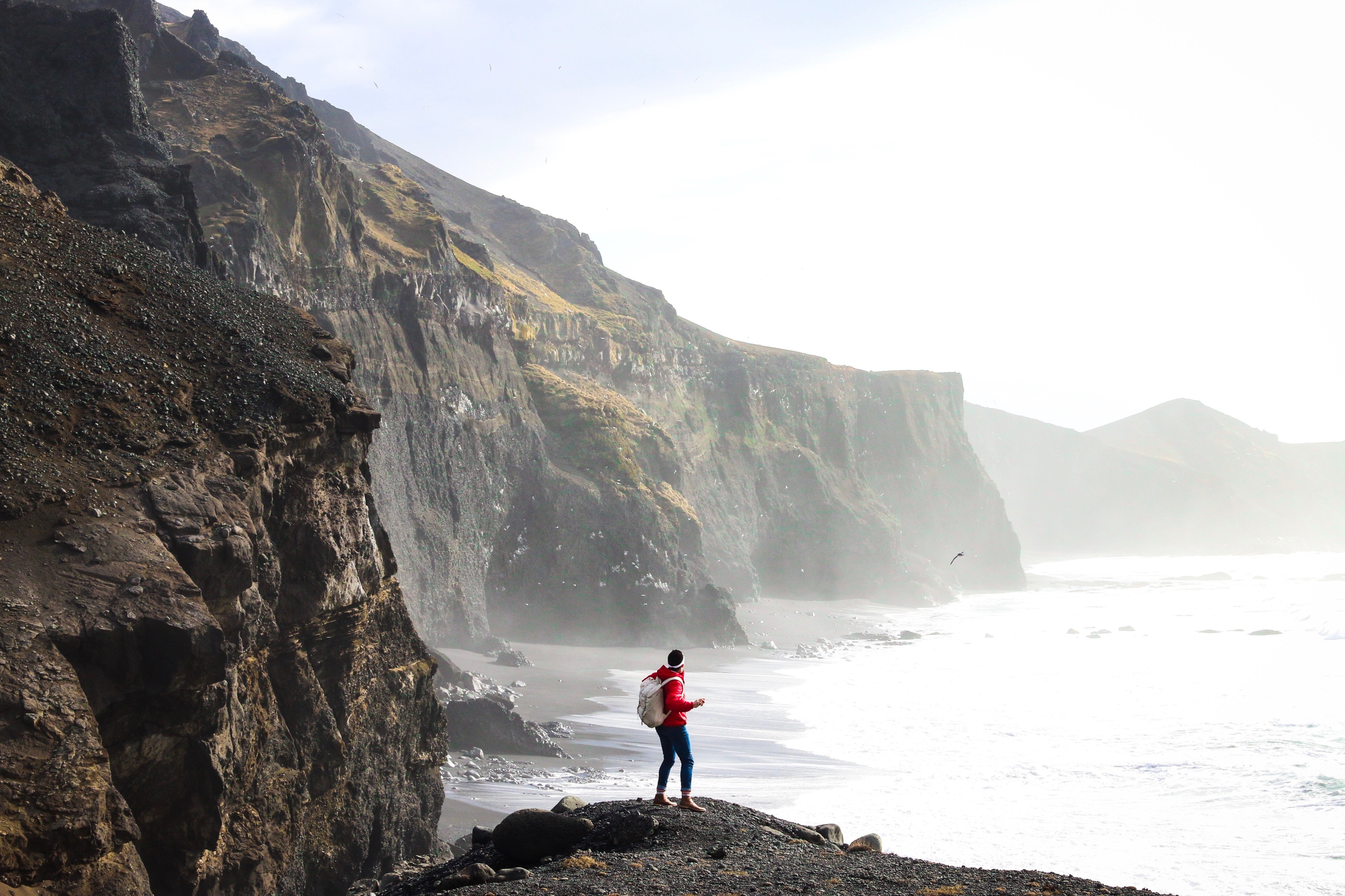 Person with backpack on cliff overlooking Iceland coast HD Wallpaper