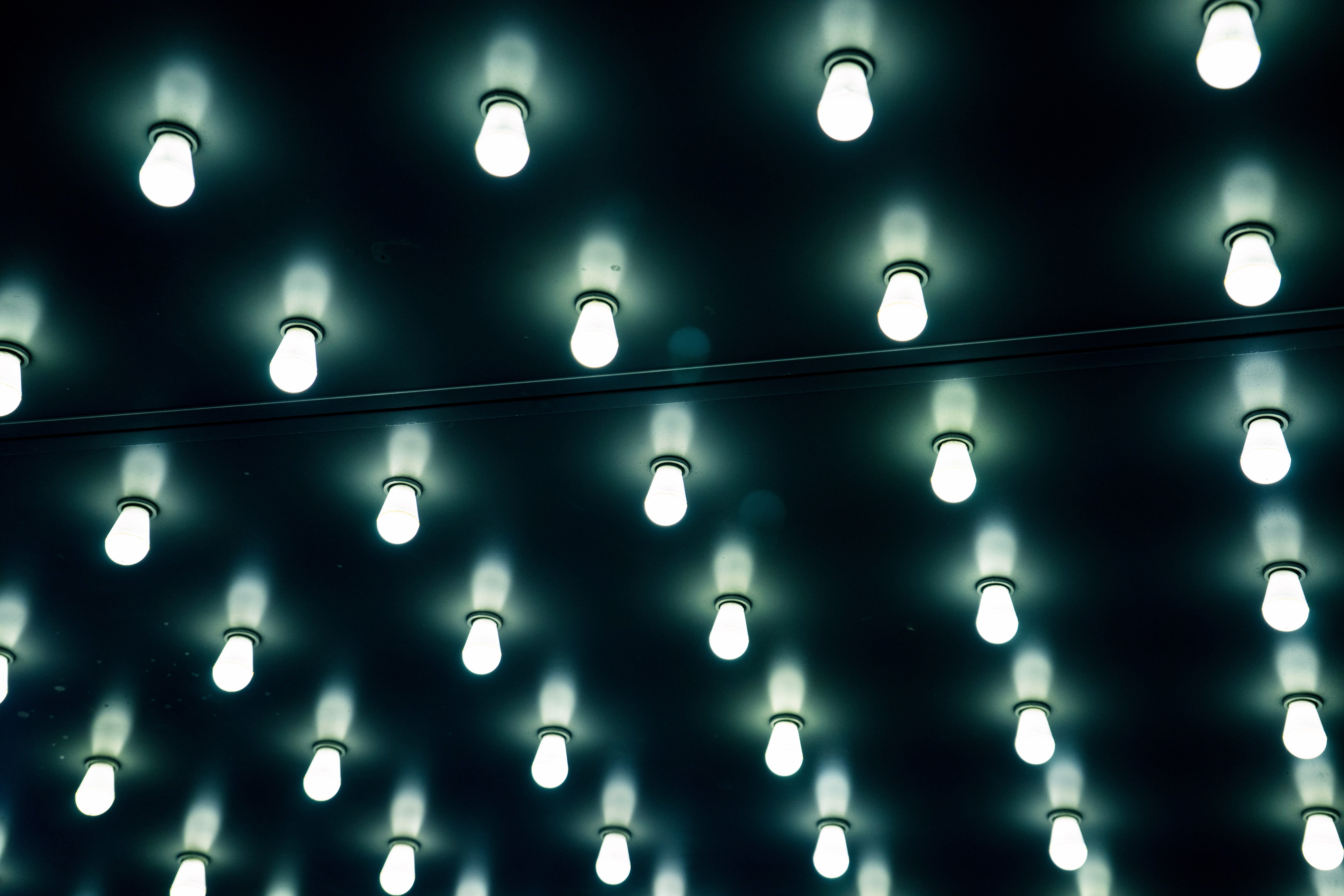 Repetitive pattern of illuminated light bulbs on a dark surface HD Wallpaper